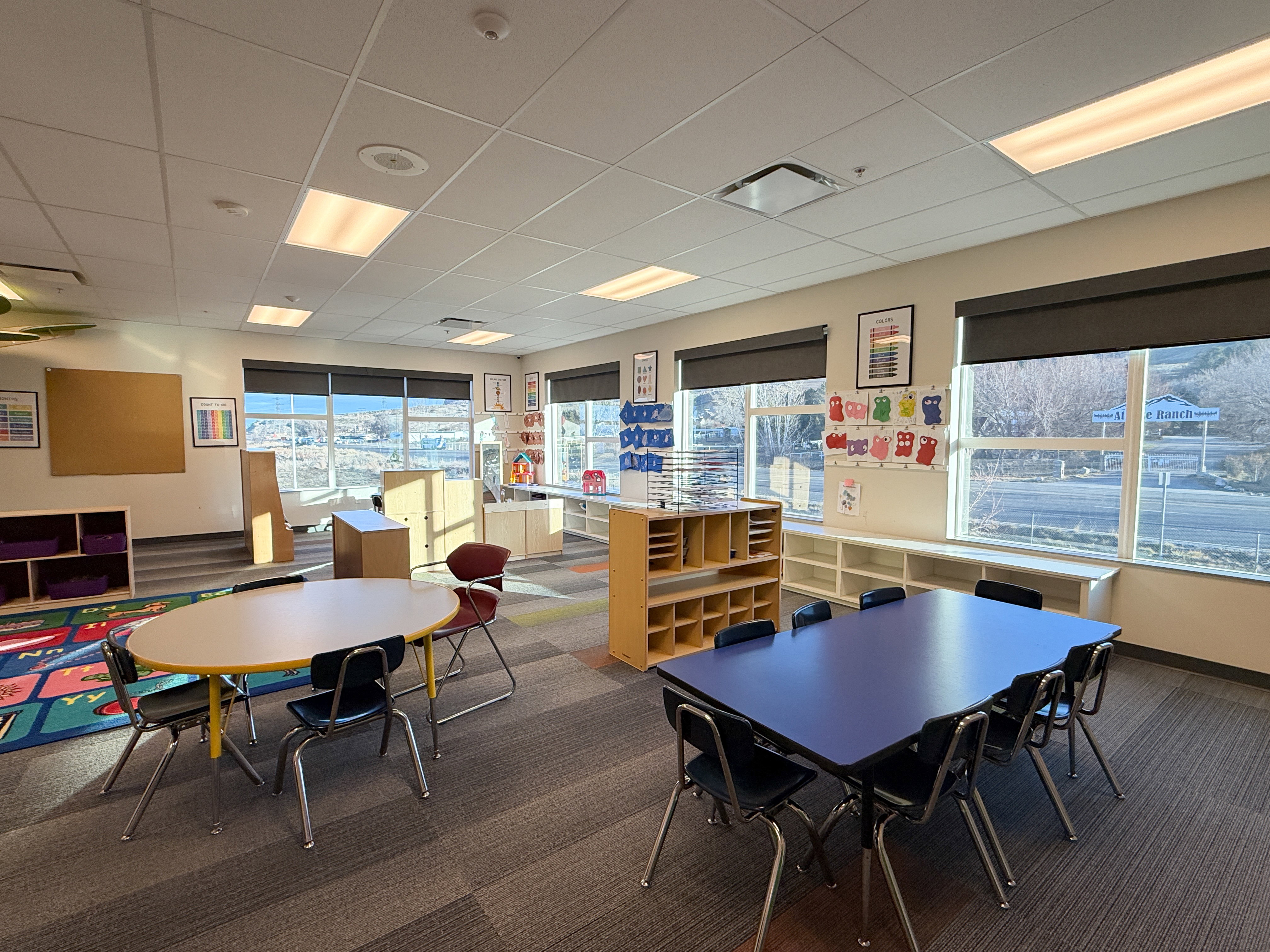 Spacious room featuring multiple large windows with roller shades, recessed lighting, and modular carpet flooring