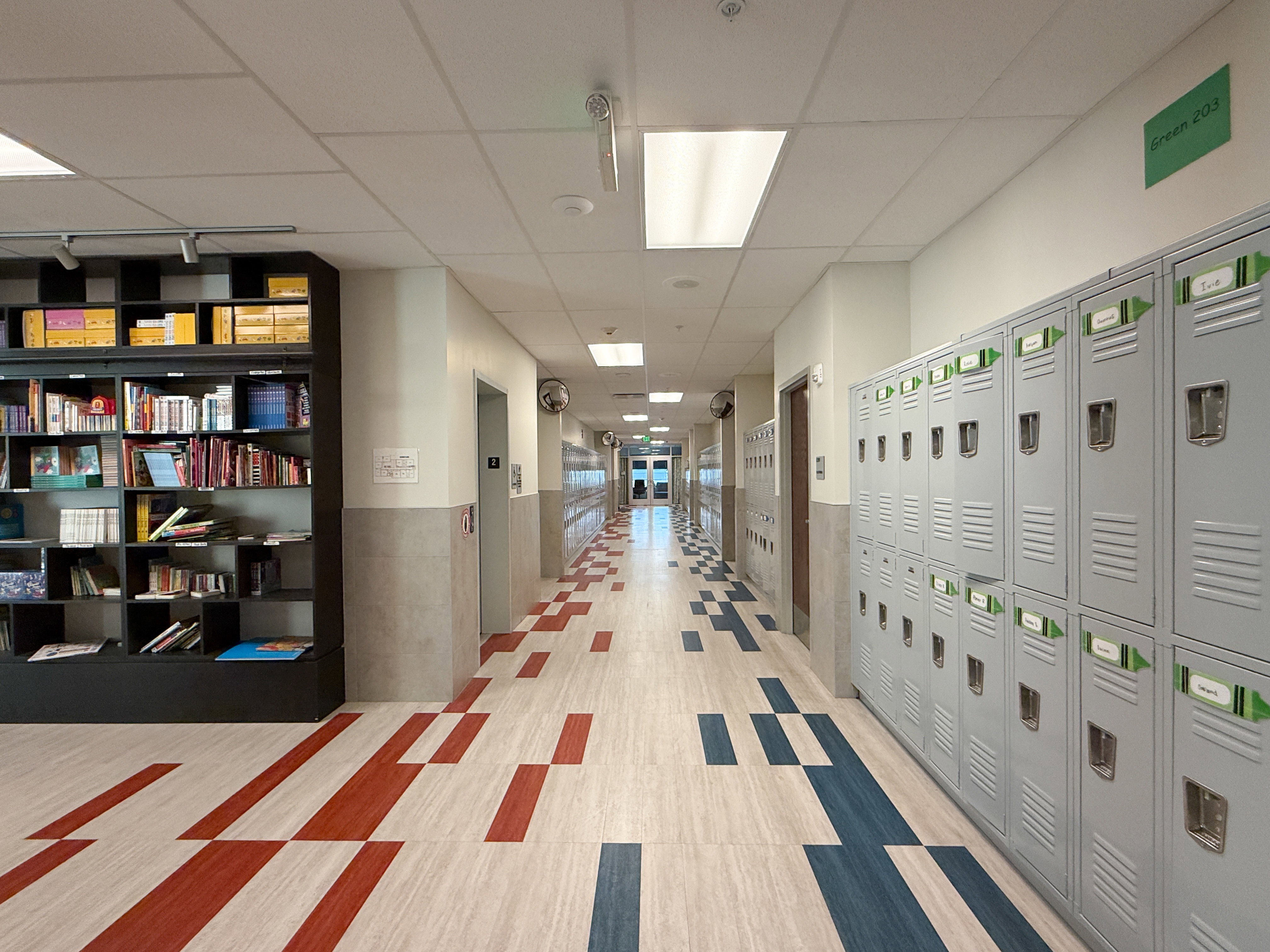 Corridor featuring patterned flooring, built-in shelving, recessed and overhead lighting, and extensive wall lockers