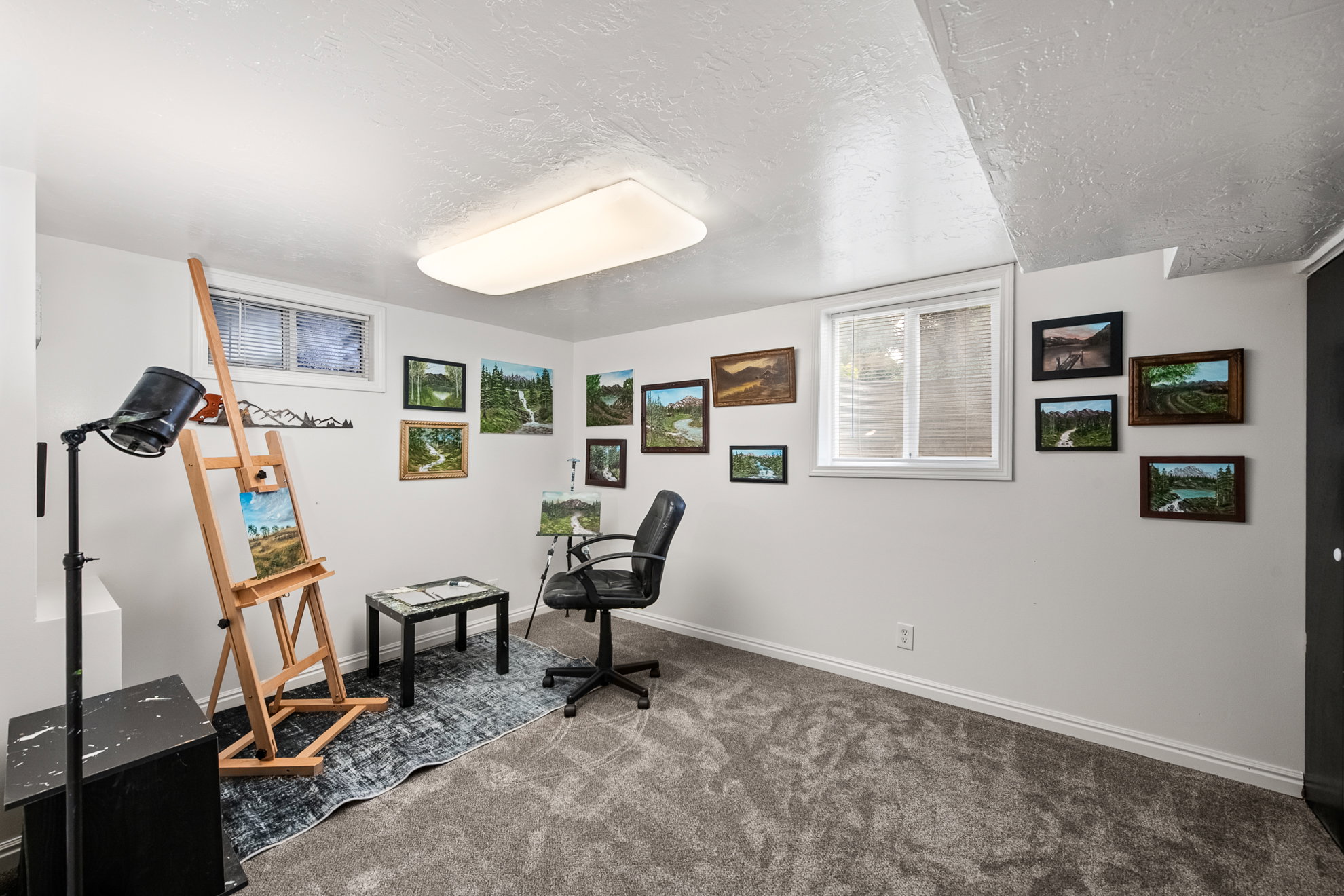 Versatile room featuring two windows with blinds, light gray wall paint, and gray carpet flooring