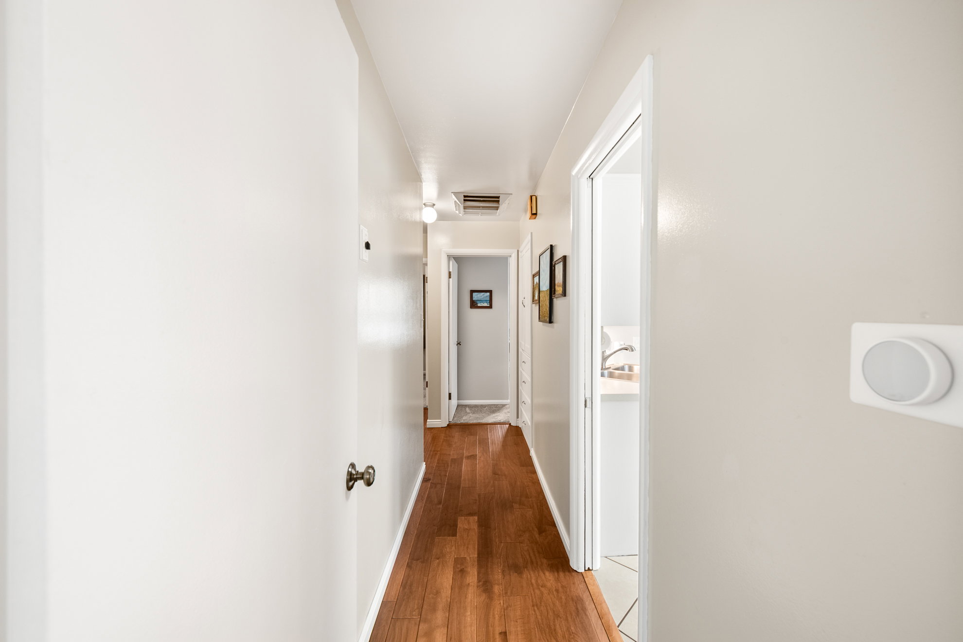 Hallway featuring warm wood-finish flooring and neutral wall tones