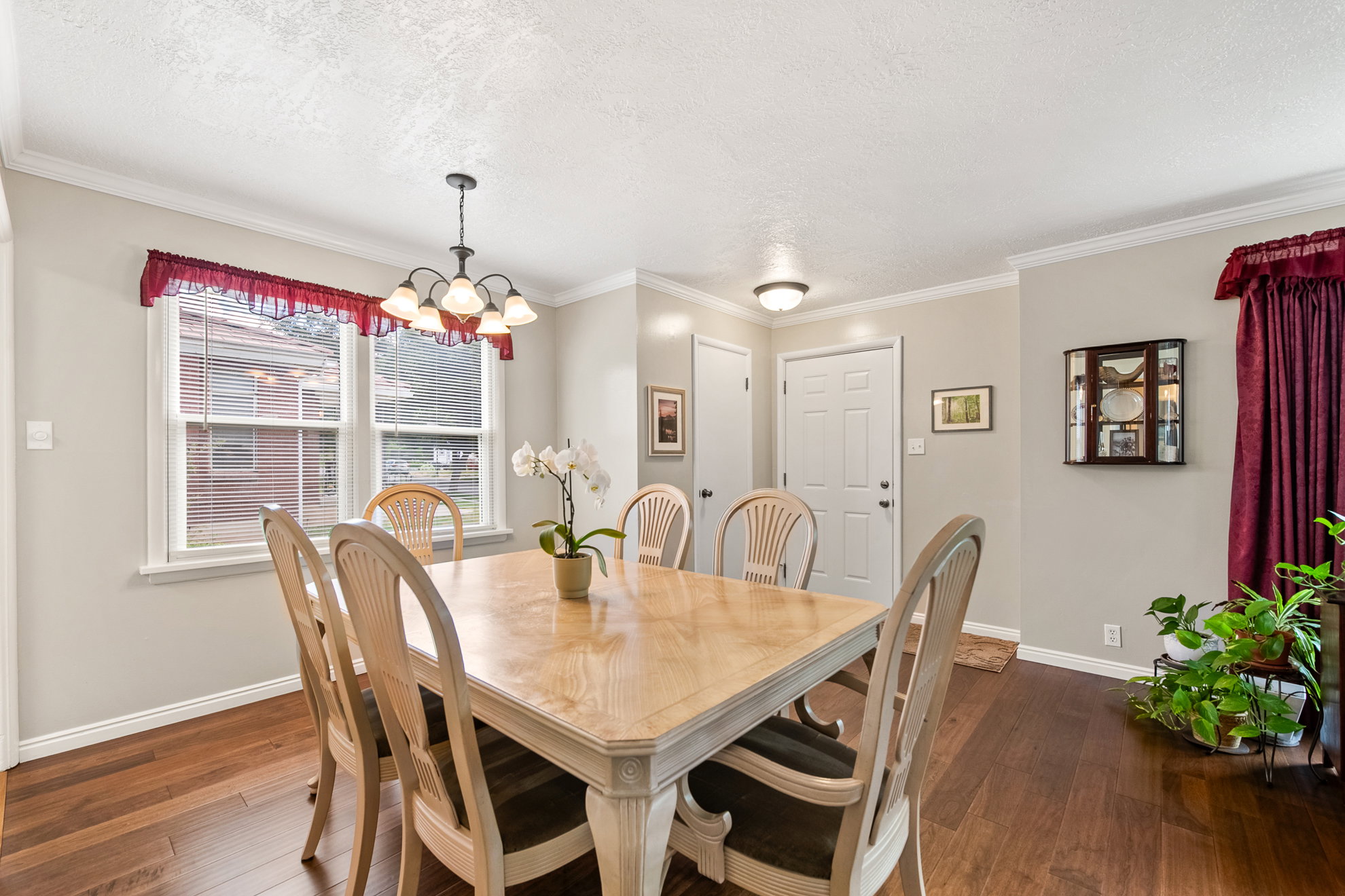 Dining area featuring wood-finish flooring, a multi-light chandelier, crown molding, and a white paneled entry door