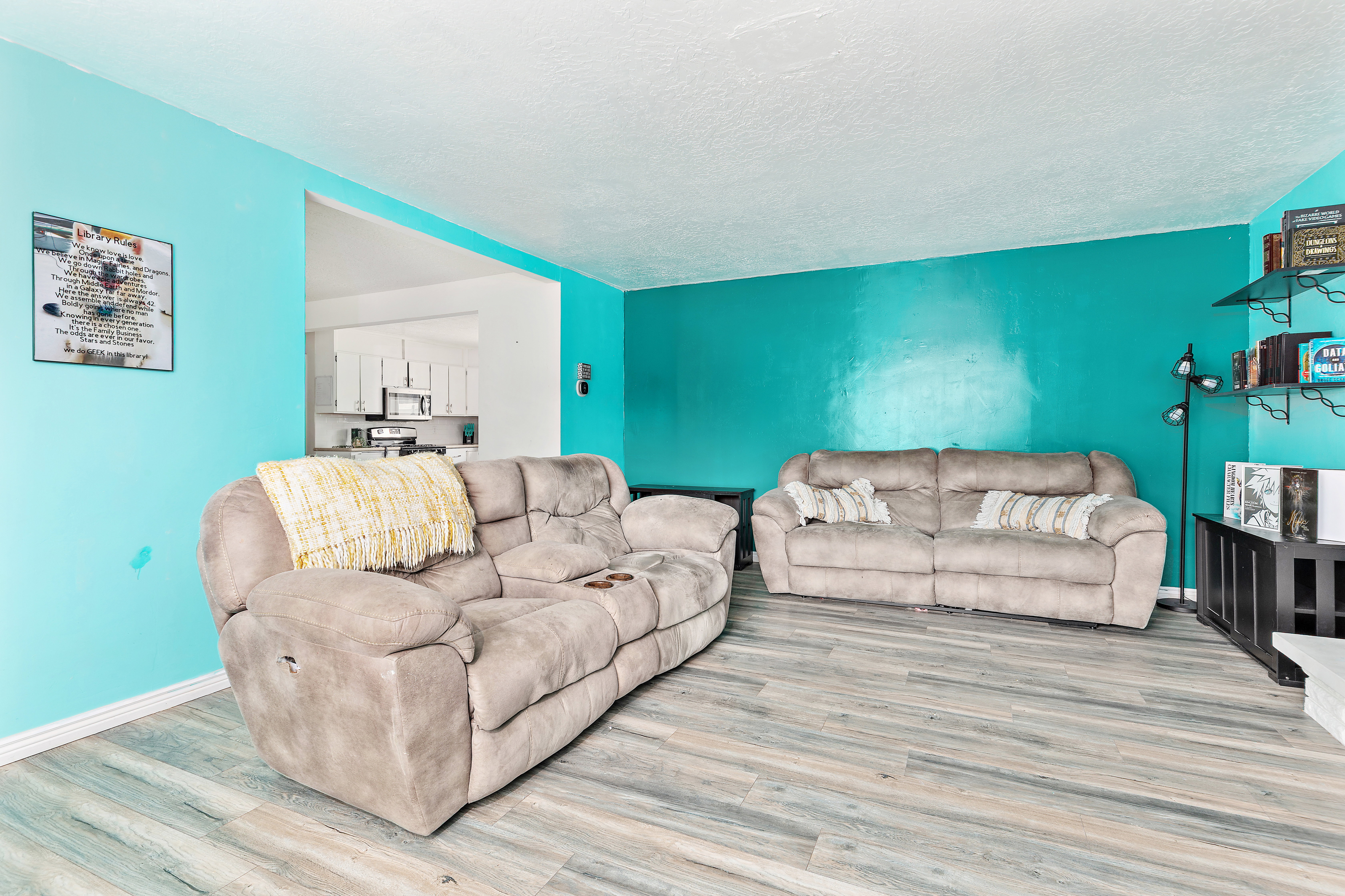 Living area featuring wood-finish flooring, vibrant wall colors, and an open pass-through to a kitchen space
