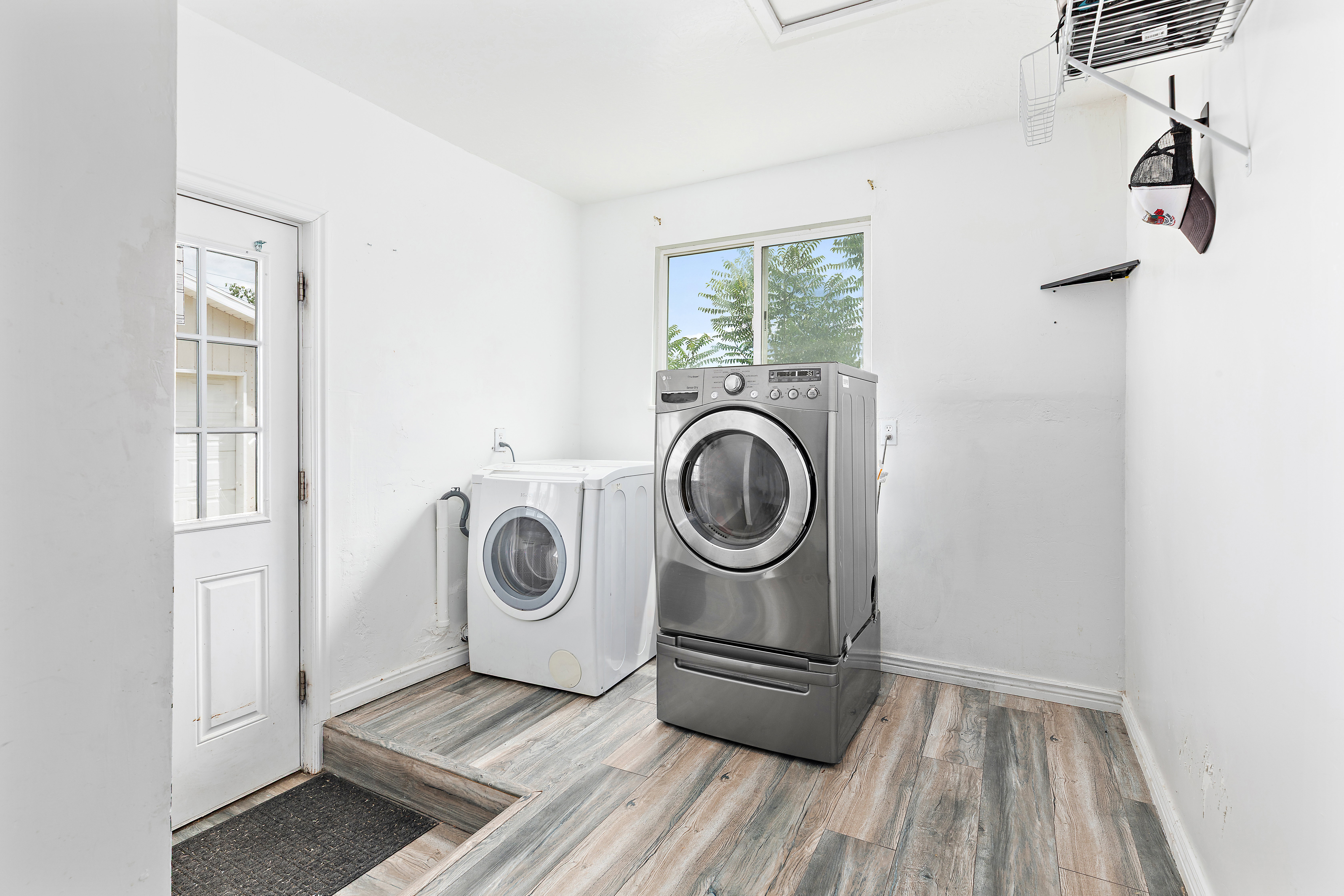 Laundry area featuring wood-finish flooring, white walls, and a window providing natural light