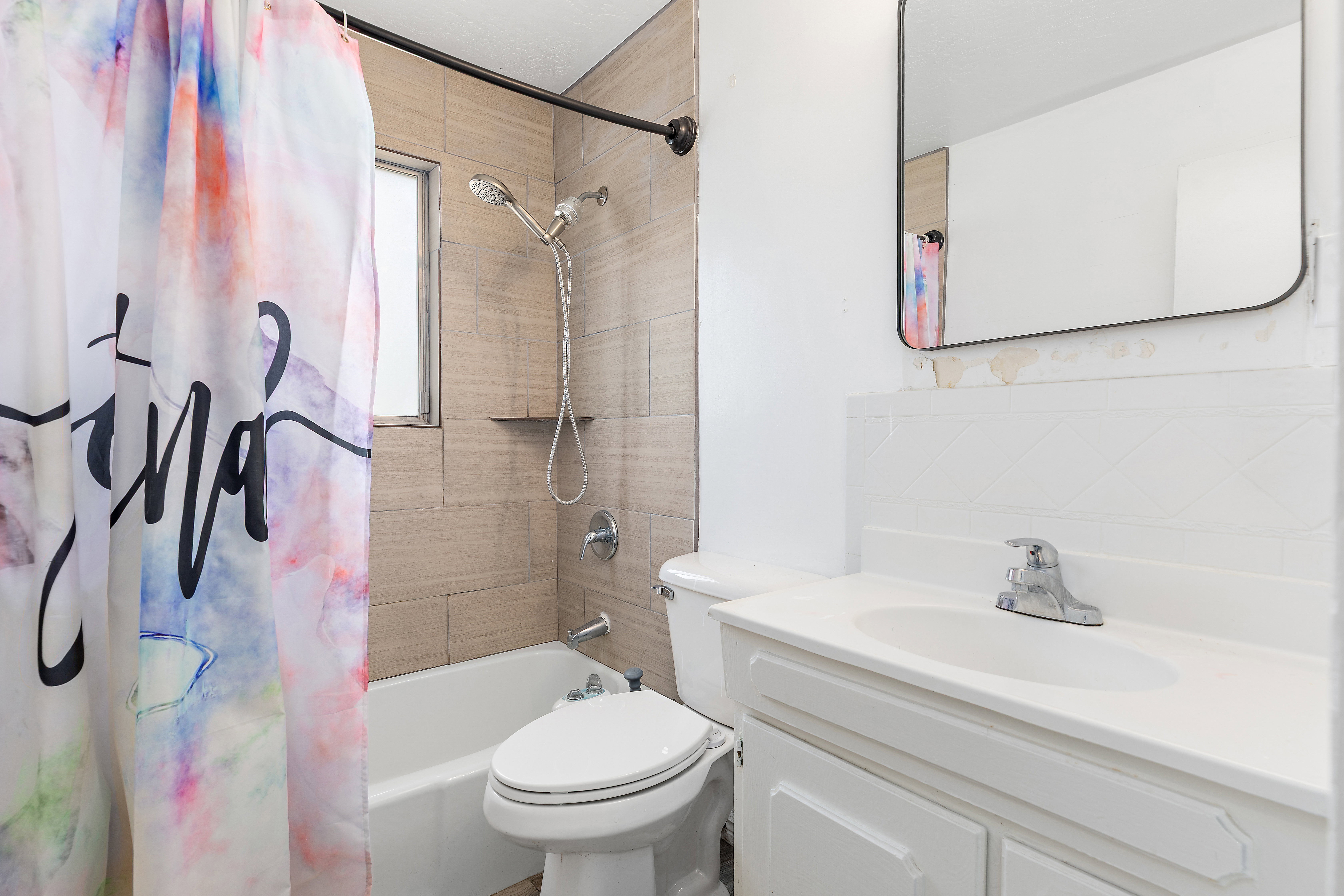 Bathroom featuring a shower-tub combination with tile surround, a built-in shower niche, and a window