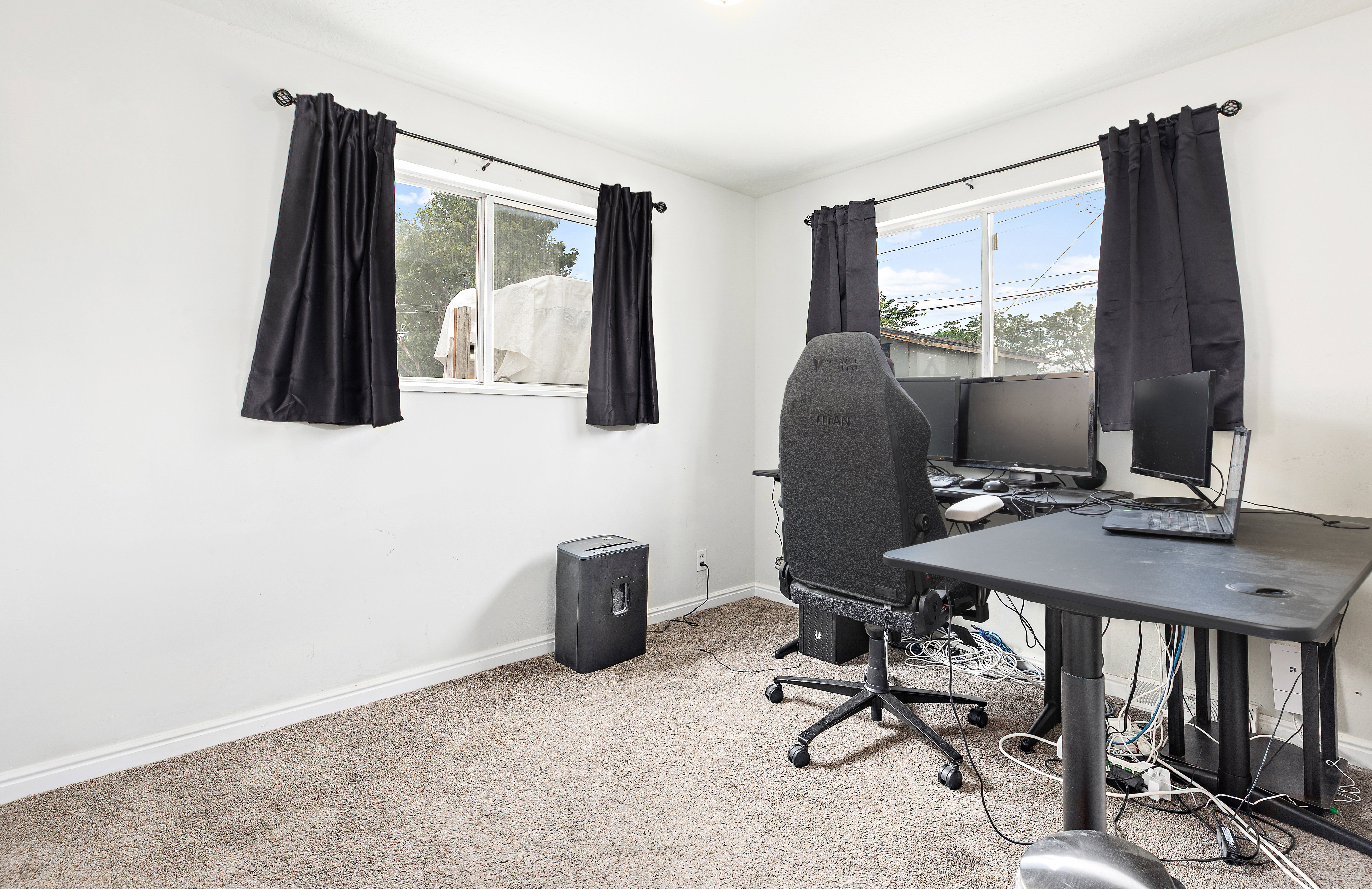 Carpeted room with white walls, baseboards, and two windows