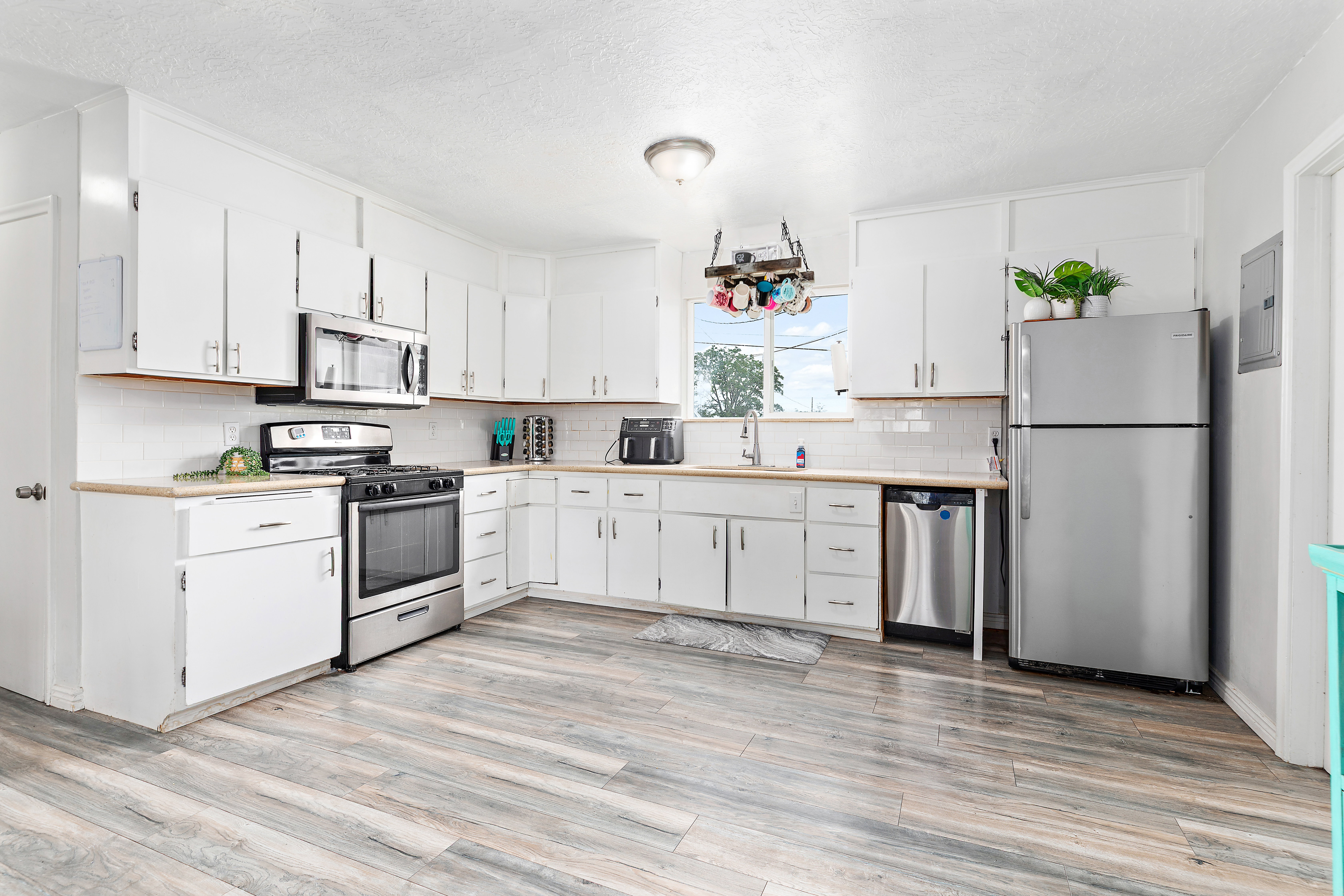 Kitchen featuring wood-finish flooring, white cabinetry, light wood-finish countertops, subway tile backsplash, and stainless steel appliances