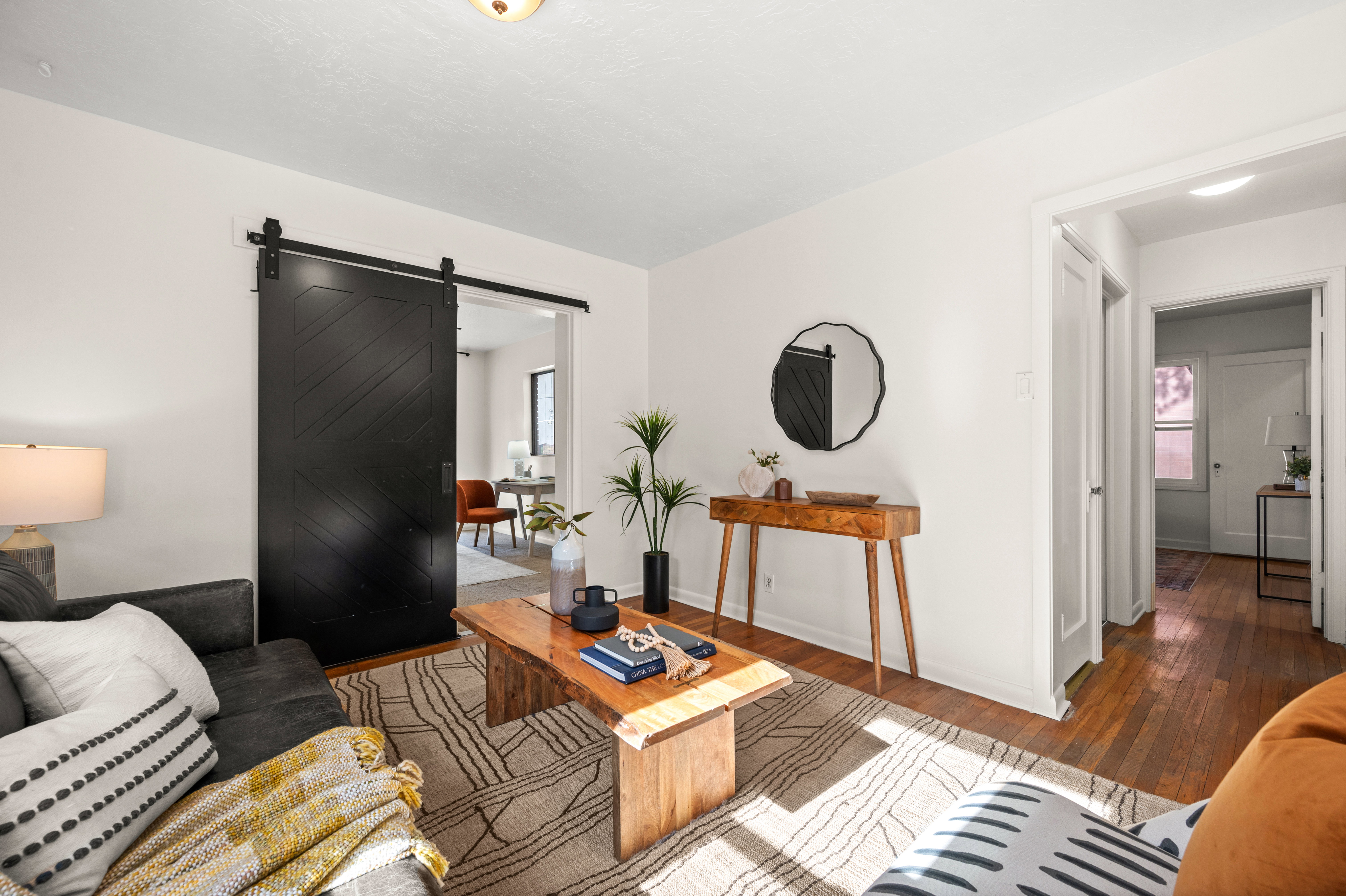 Living space featuring white walls, wood-finish flooring, and a large black barn door