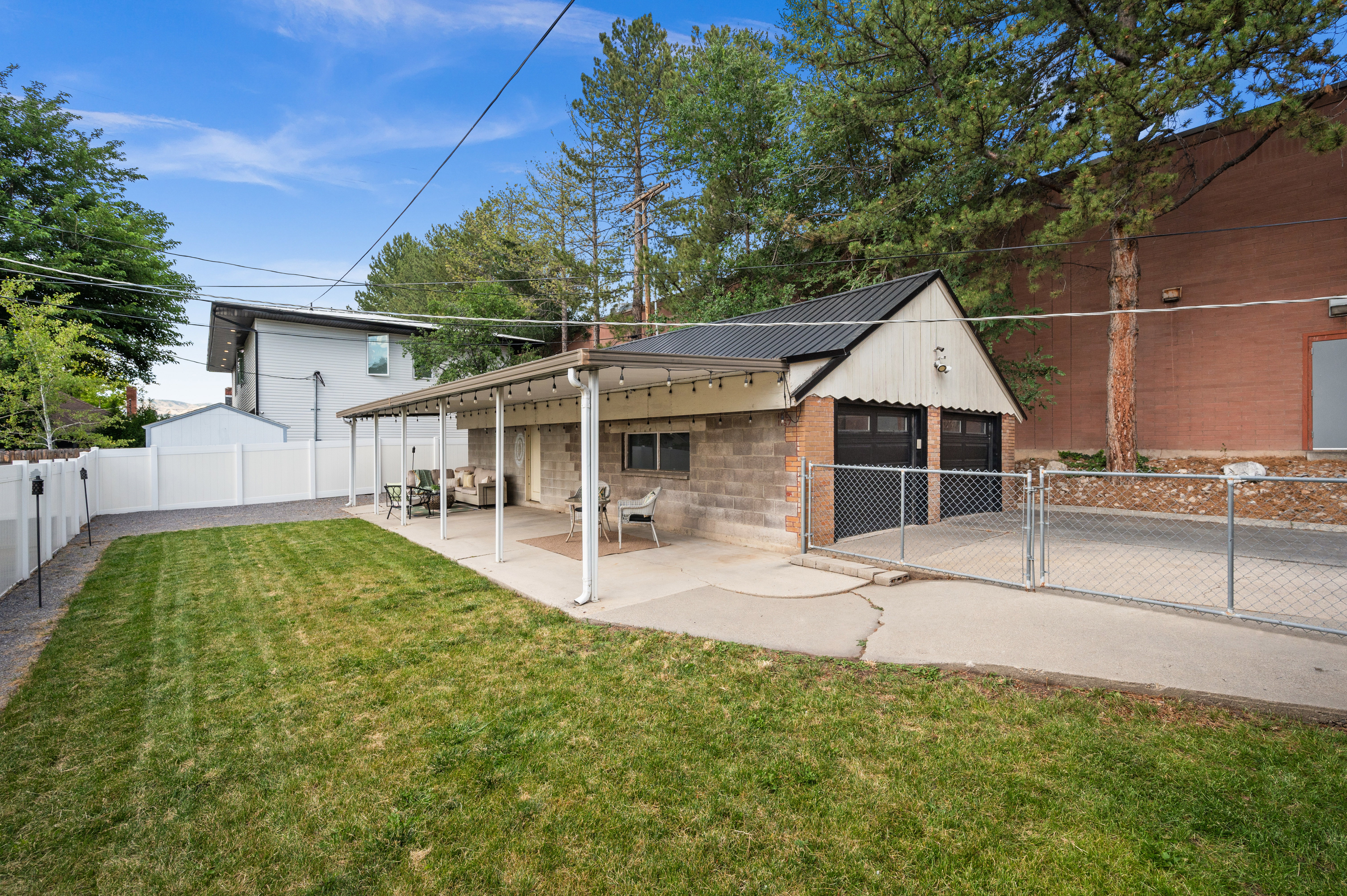 Expansive backyard featuring a manicured lawn, a full-length covered patio, and a detached garage with two bay doors