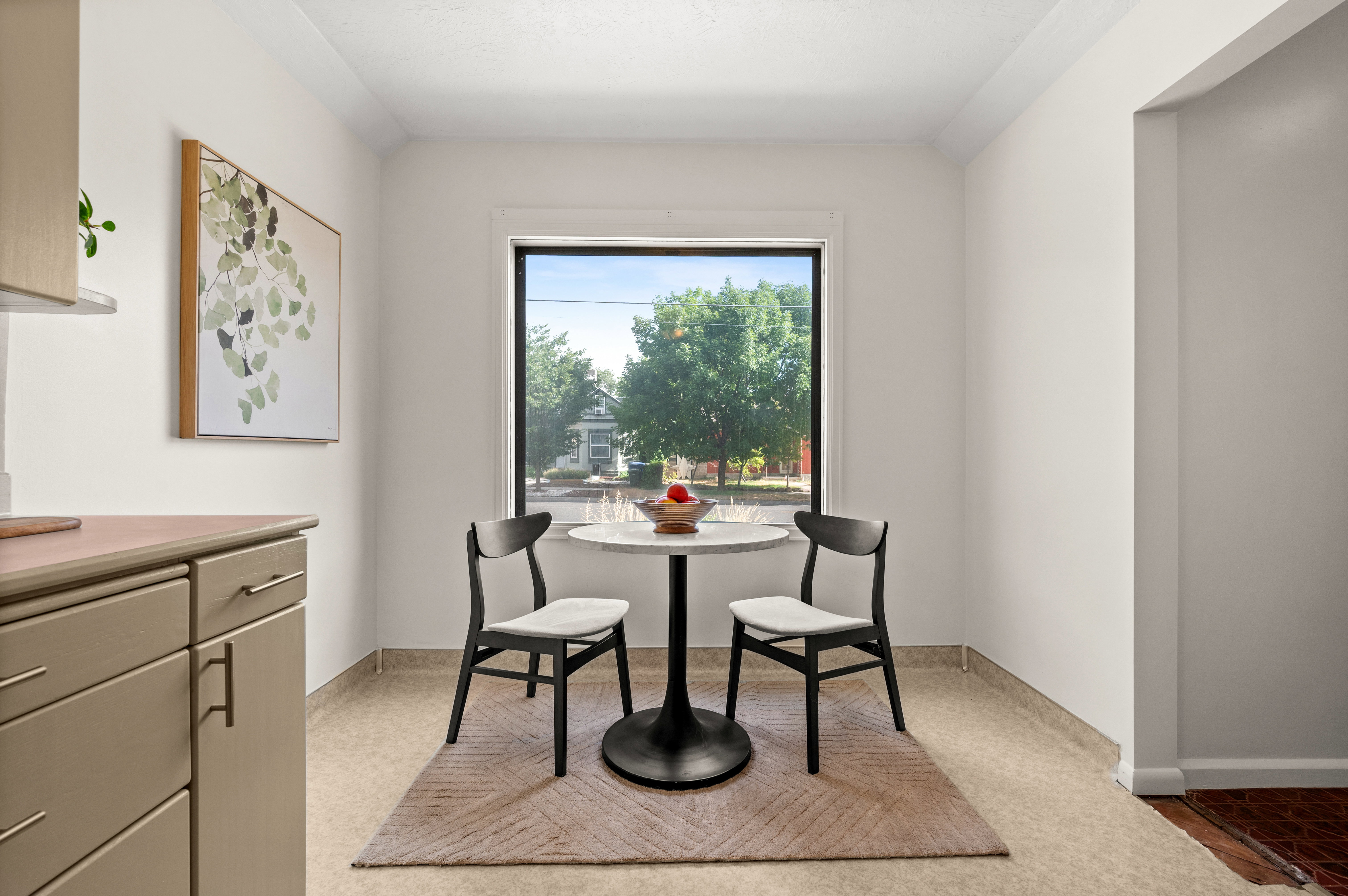 Bright dining area featuring a large window, neutral wall tones, and light-colored flooring