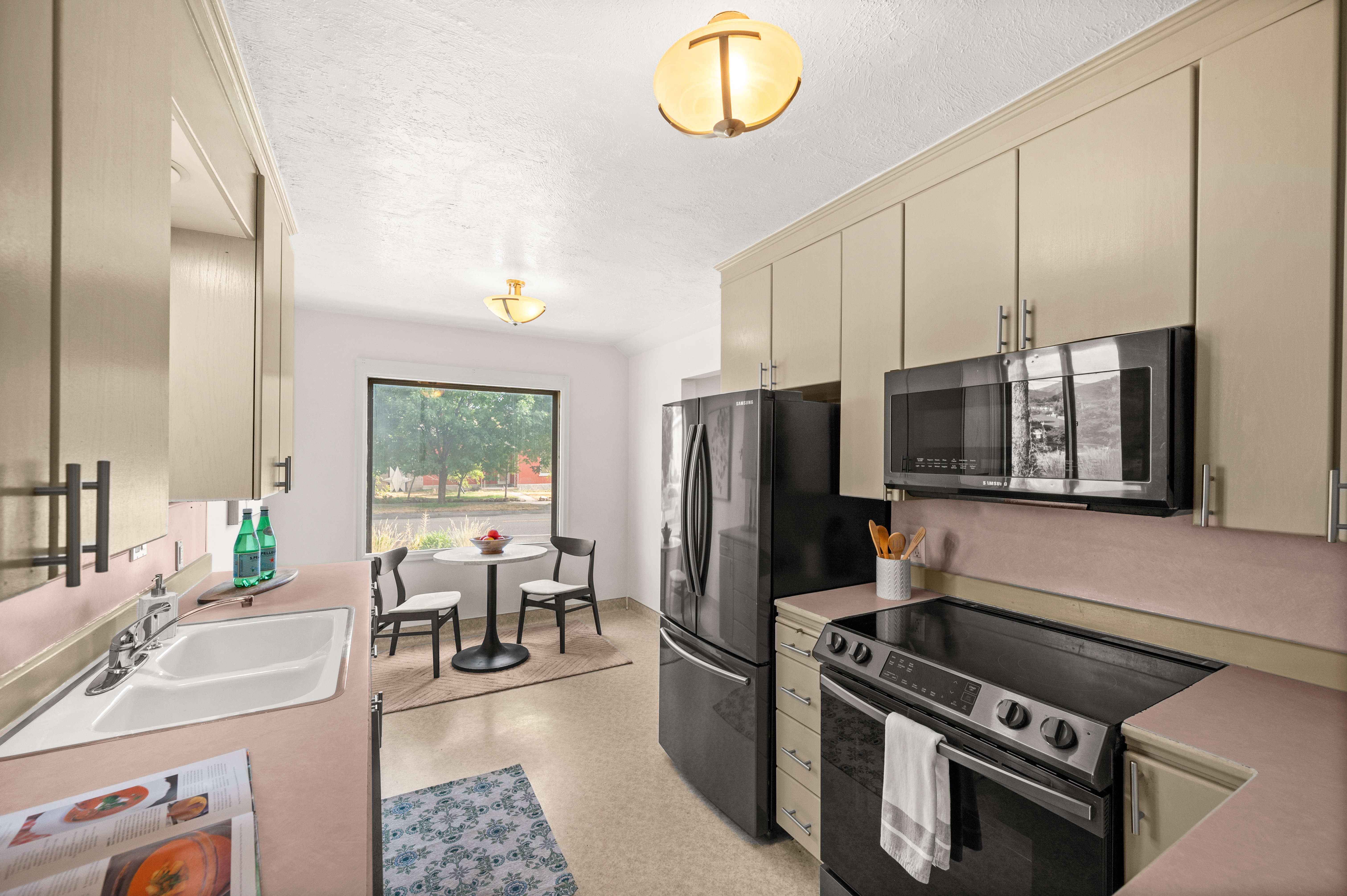 Kitchen featuring black appliance suite, ample cabinetry, integrated sink, and an eat-in dining area with a large picture window