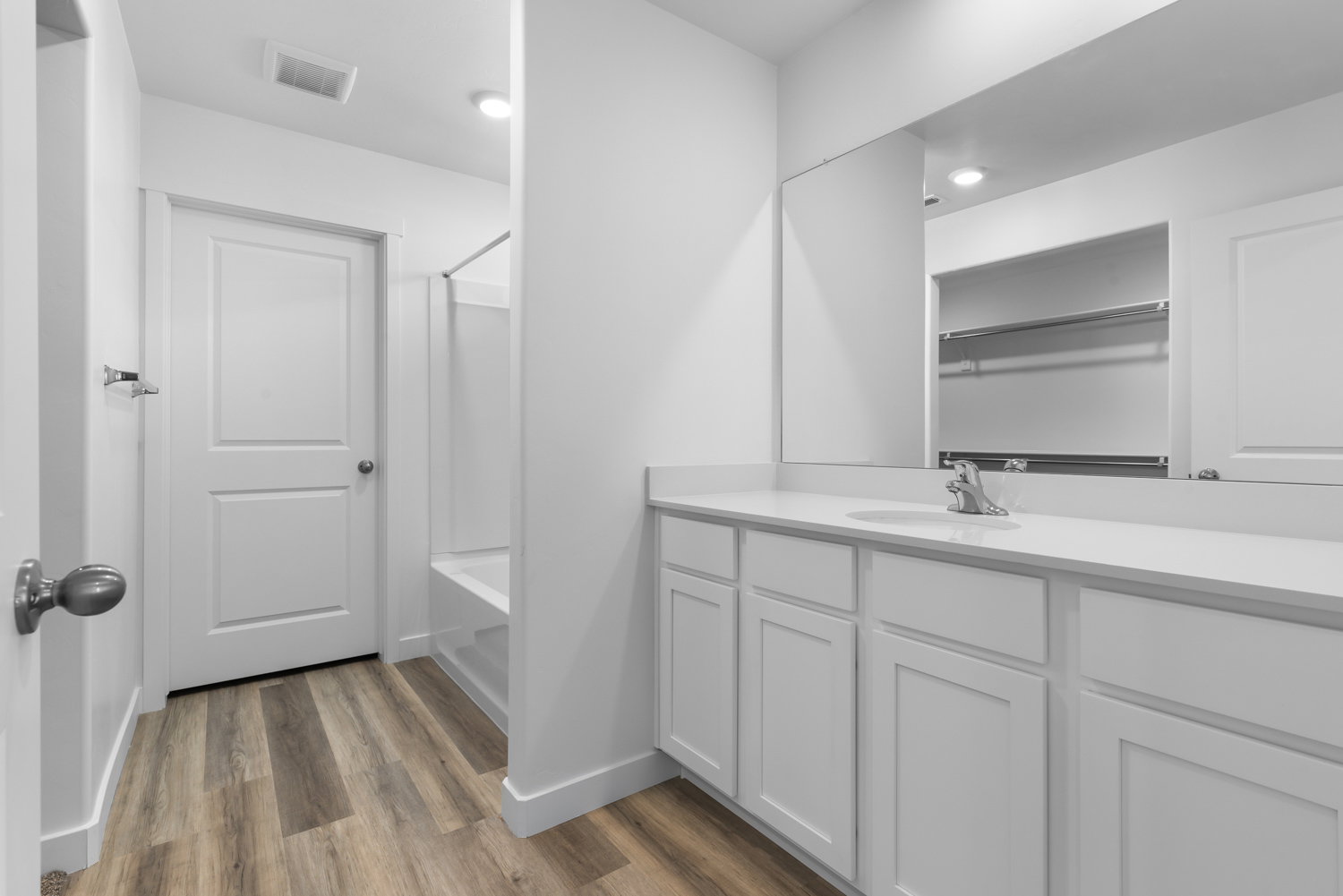 Bathroom featuring a white vanity with a single sink, an integrated countertop, and a large wall-mounted mirror