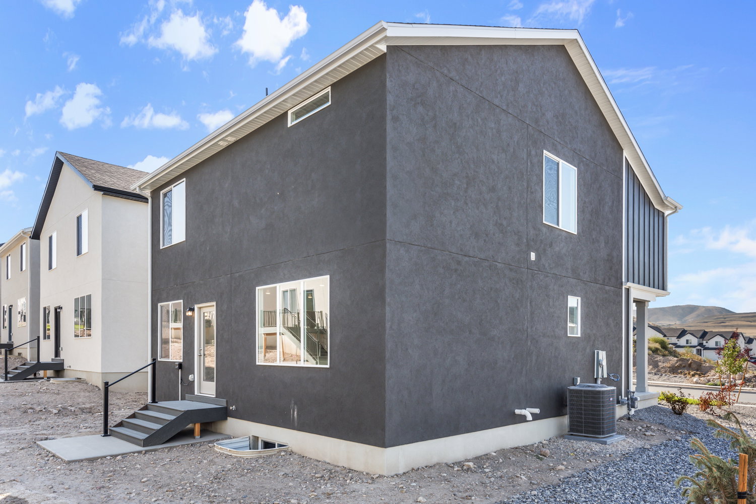 Contemporary townhome exterior featuring dark gray stucco siding and contrasting white trim