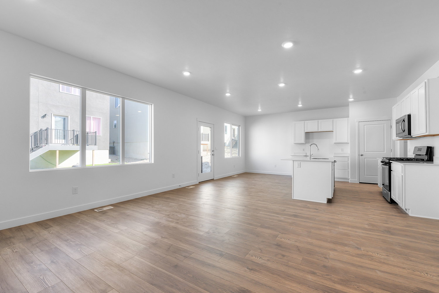 Open-concept living area featuring wood-finish flooring, recessed lighting, and a kitchen with white cabinetry