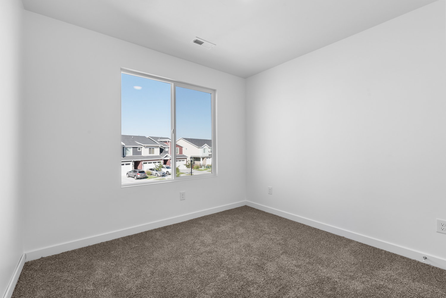 Bright interior room featuring a large window, neutral wall paint, white trim, and brown carpet flooring