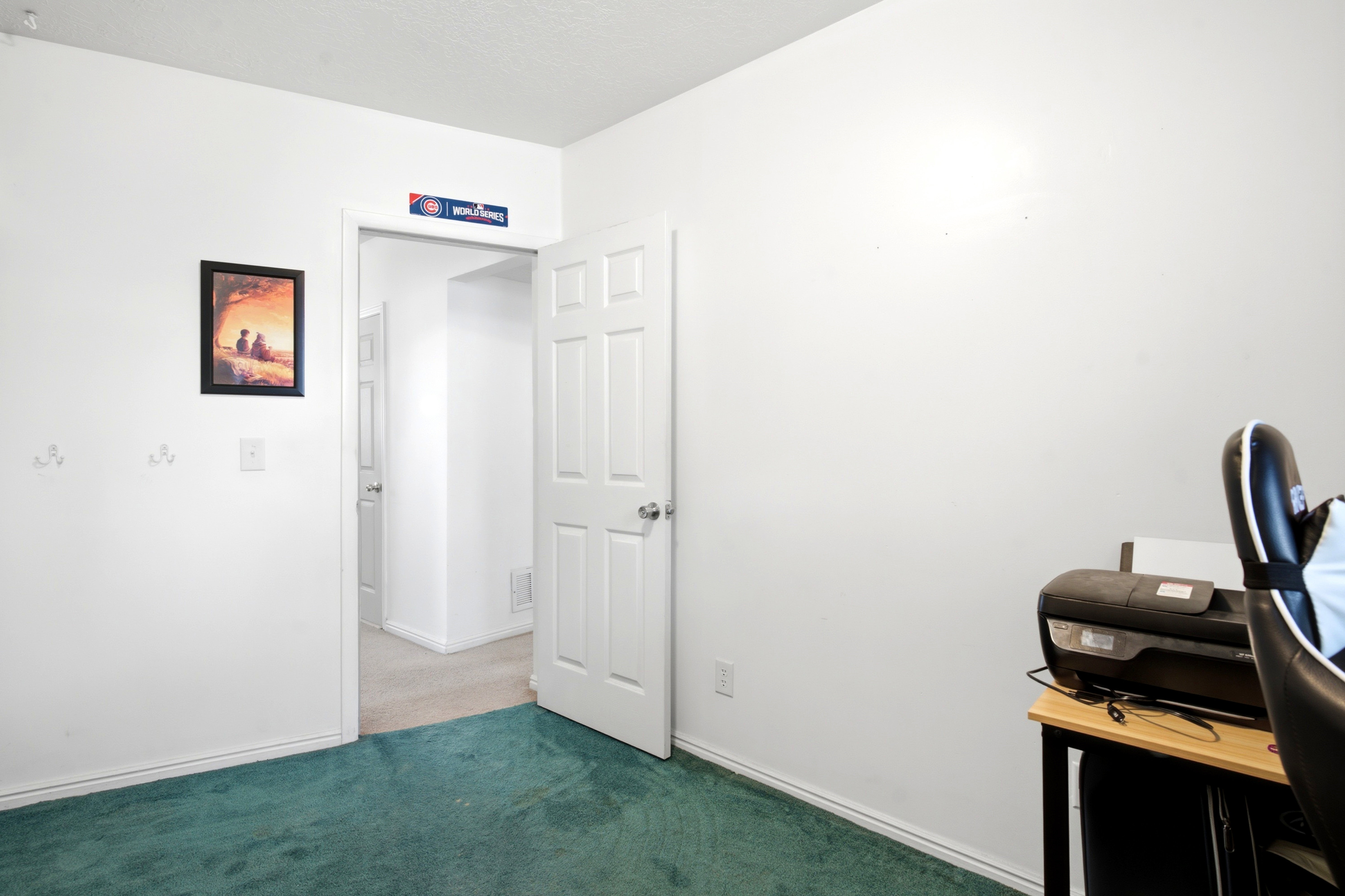 Interior room featuring white walls, teal carpeting, and a white six-panel door