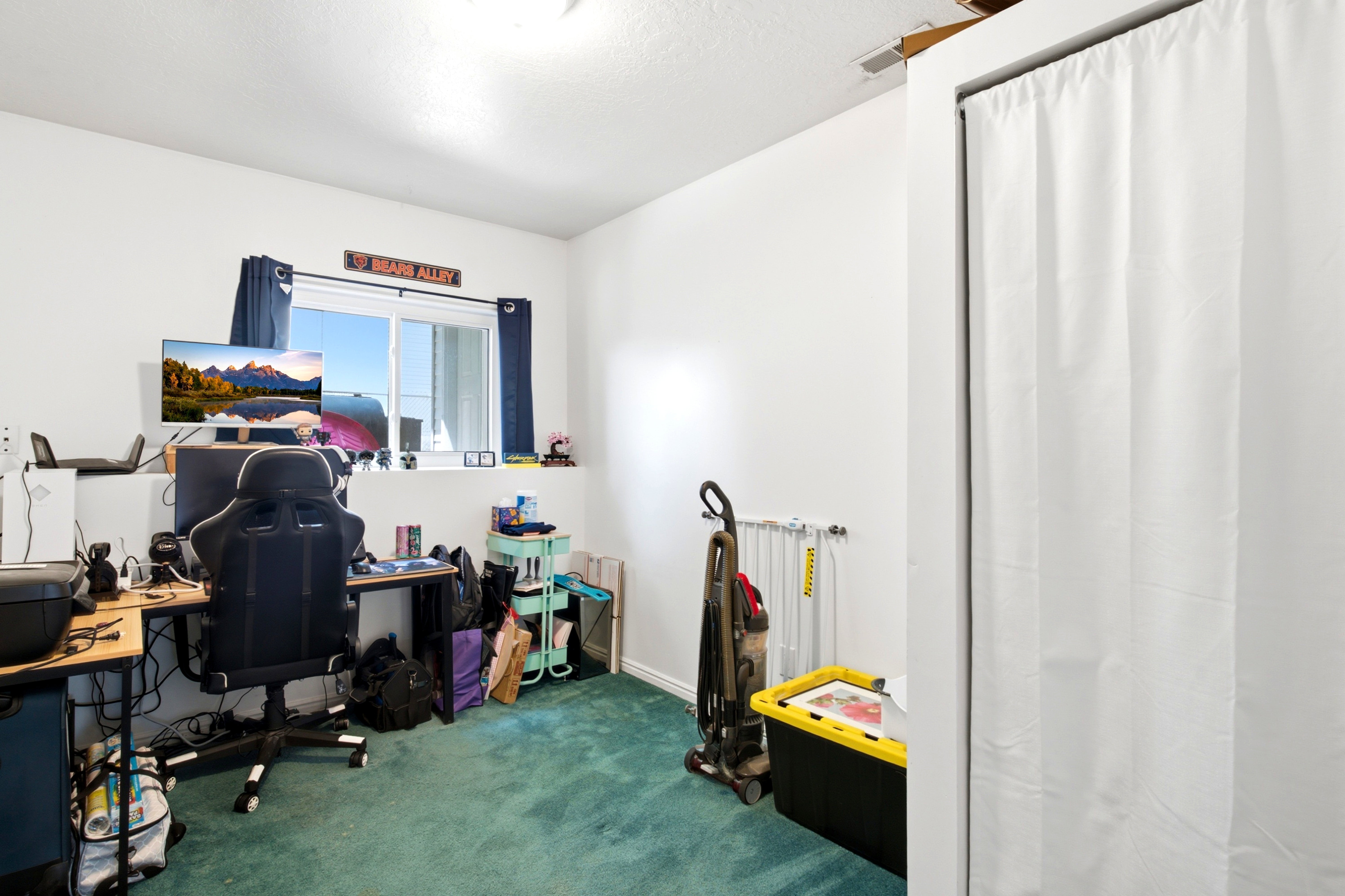 Room featuring wall-to-wall carpeting, white painted walls, and a window with dark blue curtains