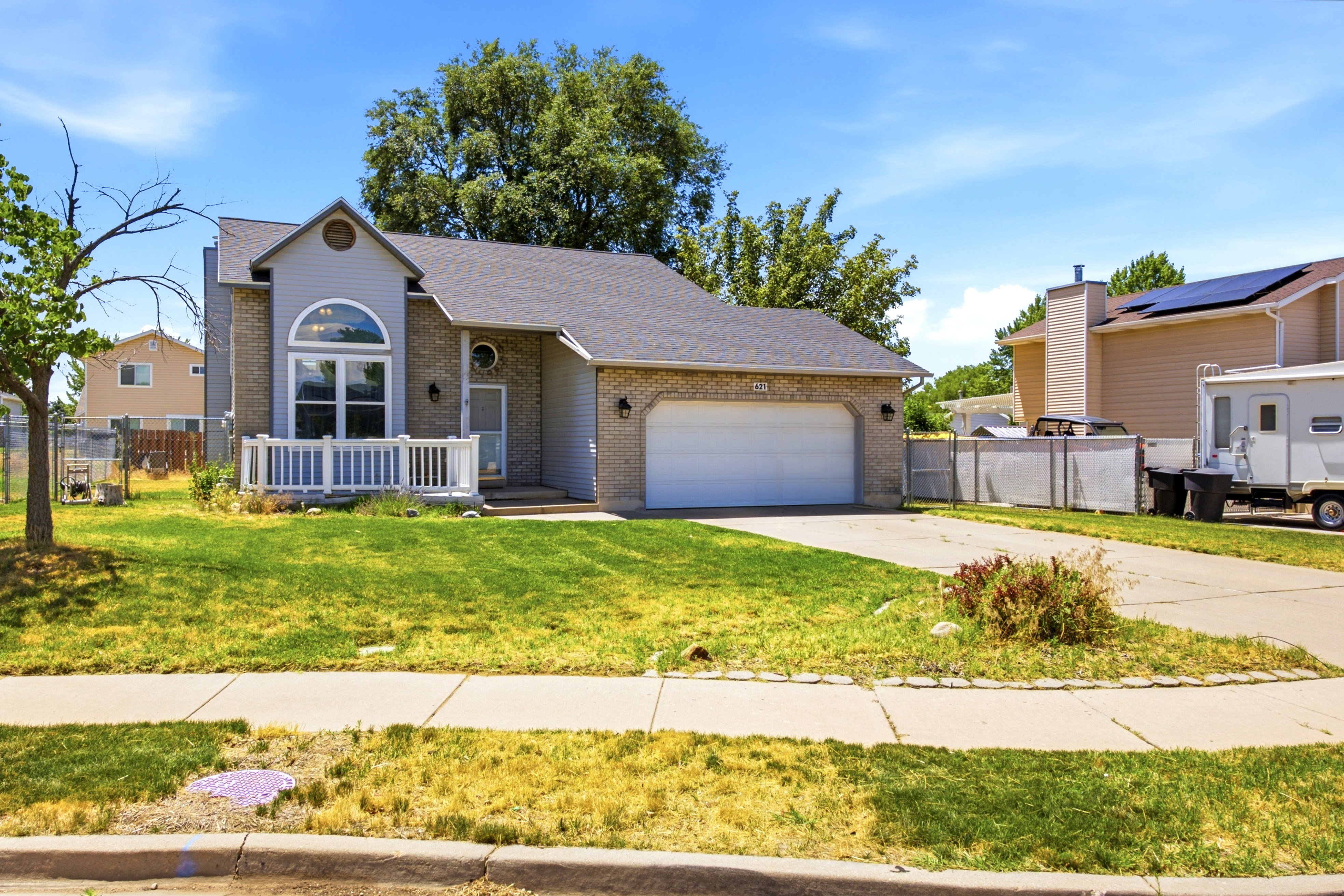 Exterior showcasing brick and siding facade, an arched window, and a white front porch railing