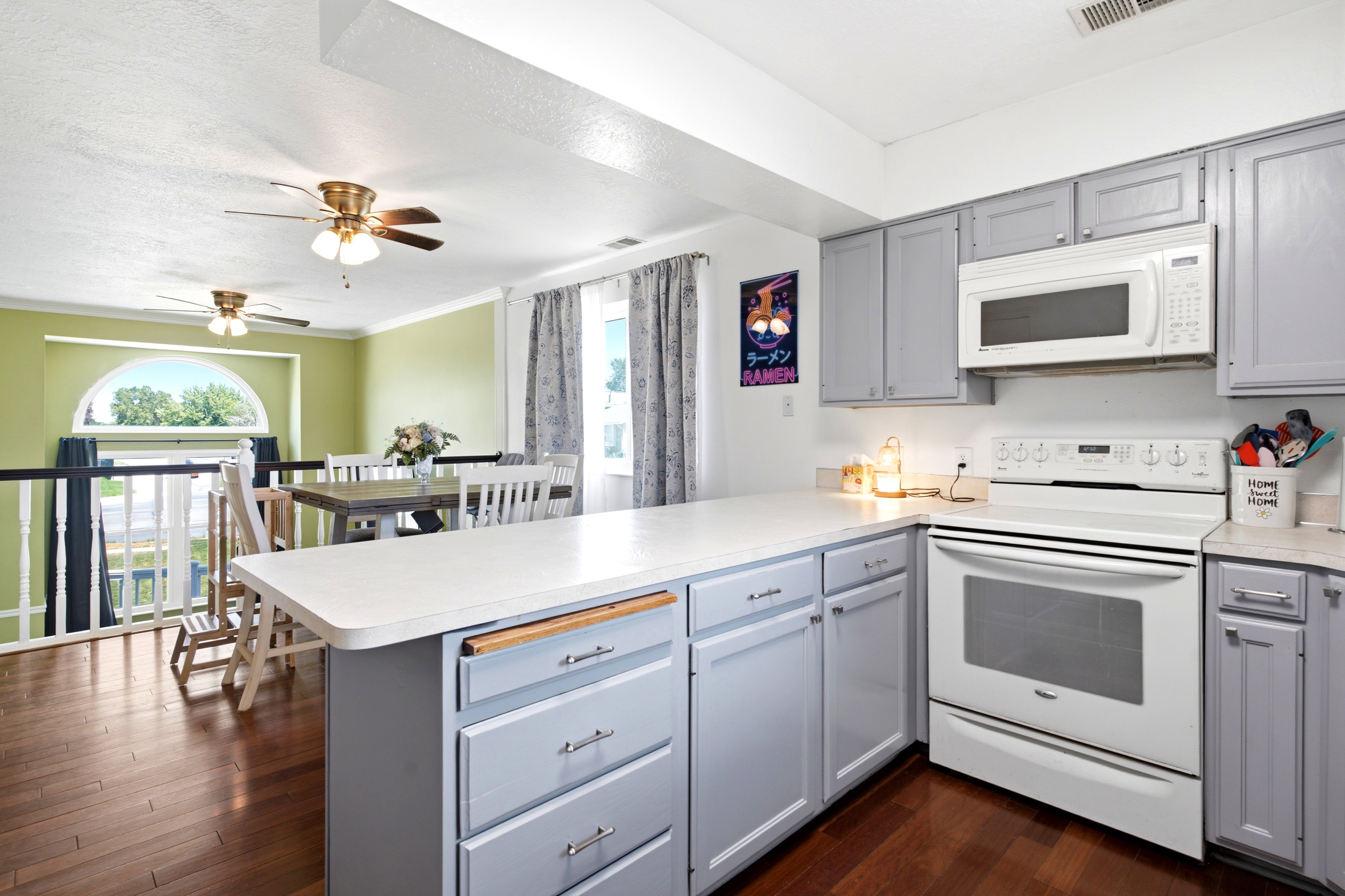 Kitchen featuring light gray cabinetry, white countertops, and white appliances