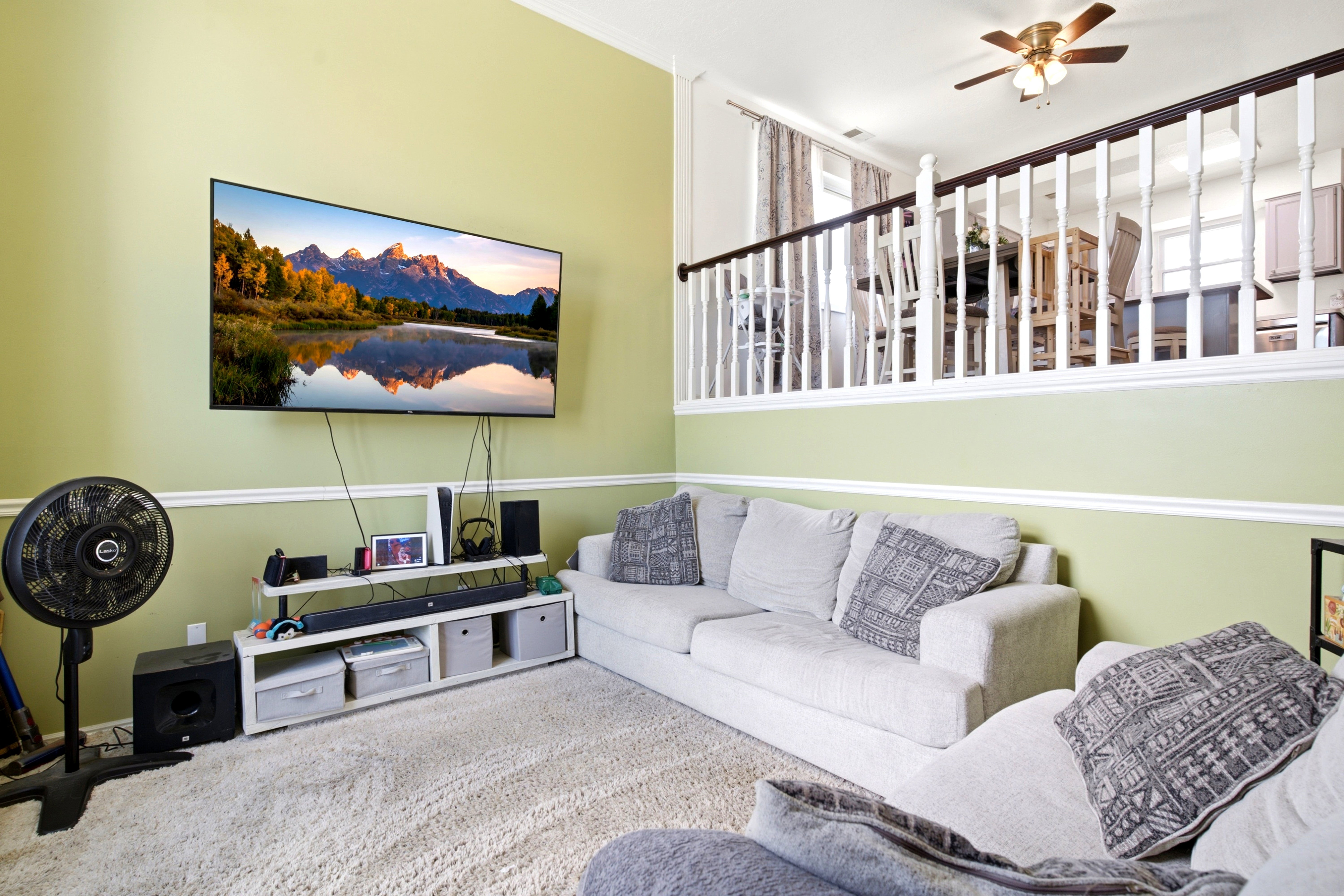 Living area featuring light green walls with white trim, high ceilings, and a carpeted floor