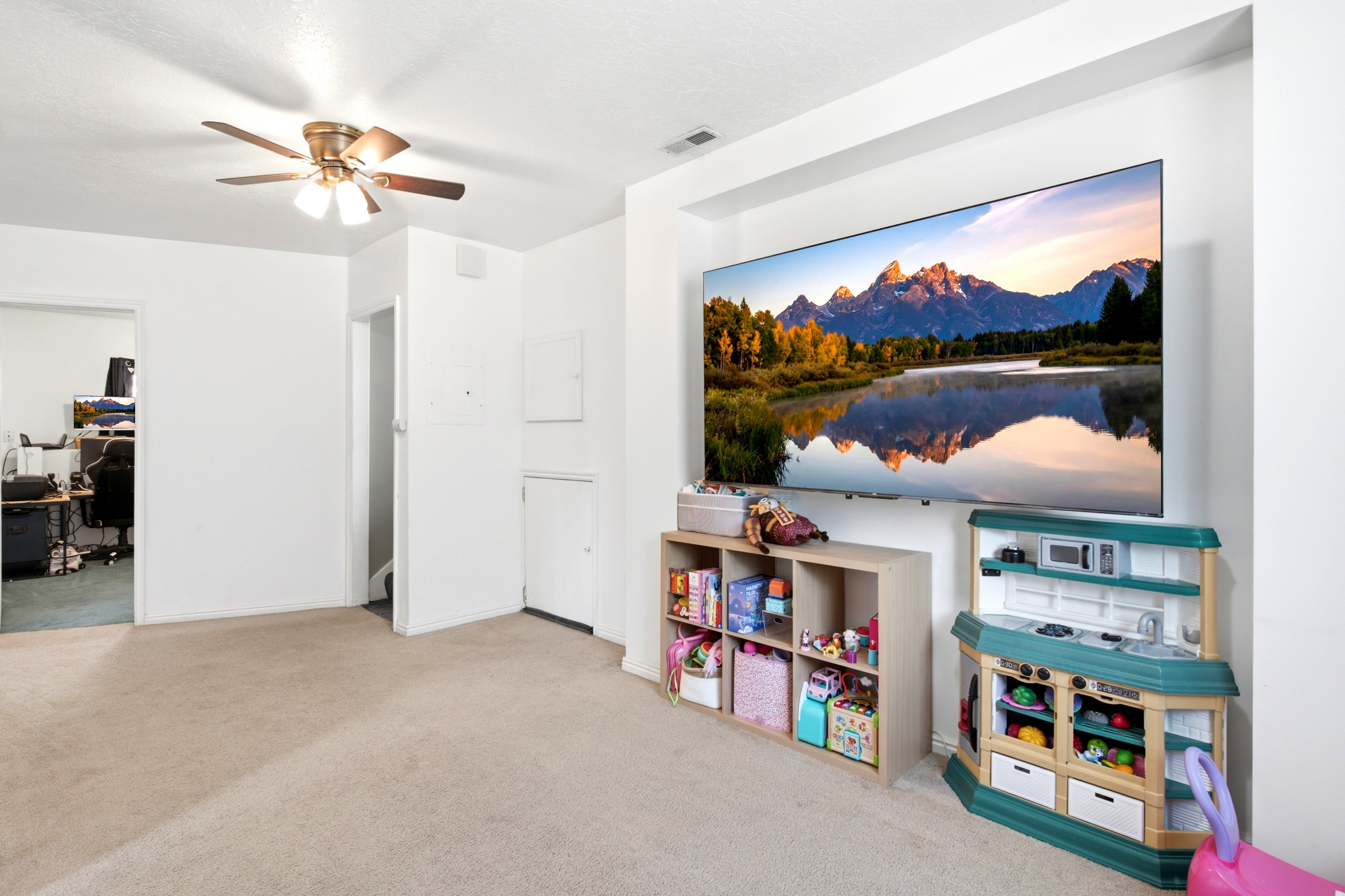 Carpeted room with a ceiling fan light fixture and white walls