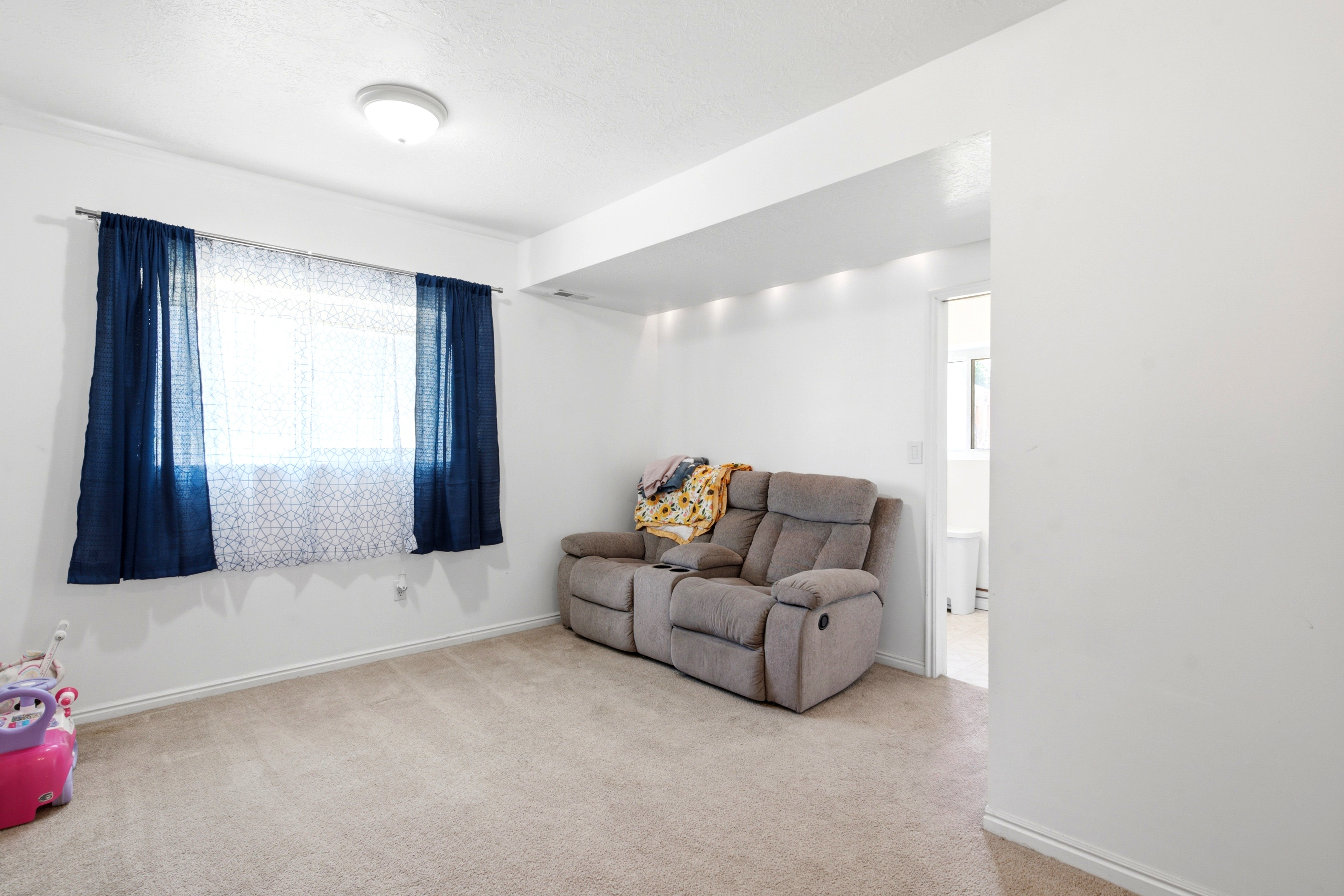 Carpeted room featuring a window with natural light, recessed lighting in a ceiling soffit, and a flush-mount ceiling light