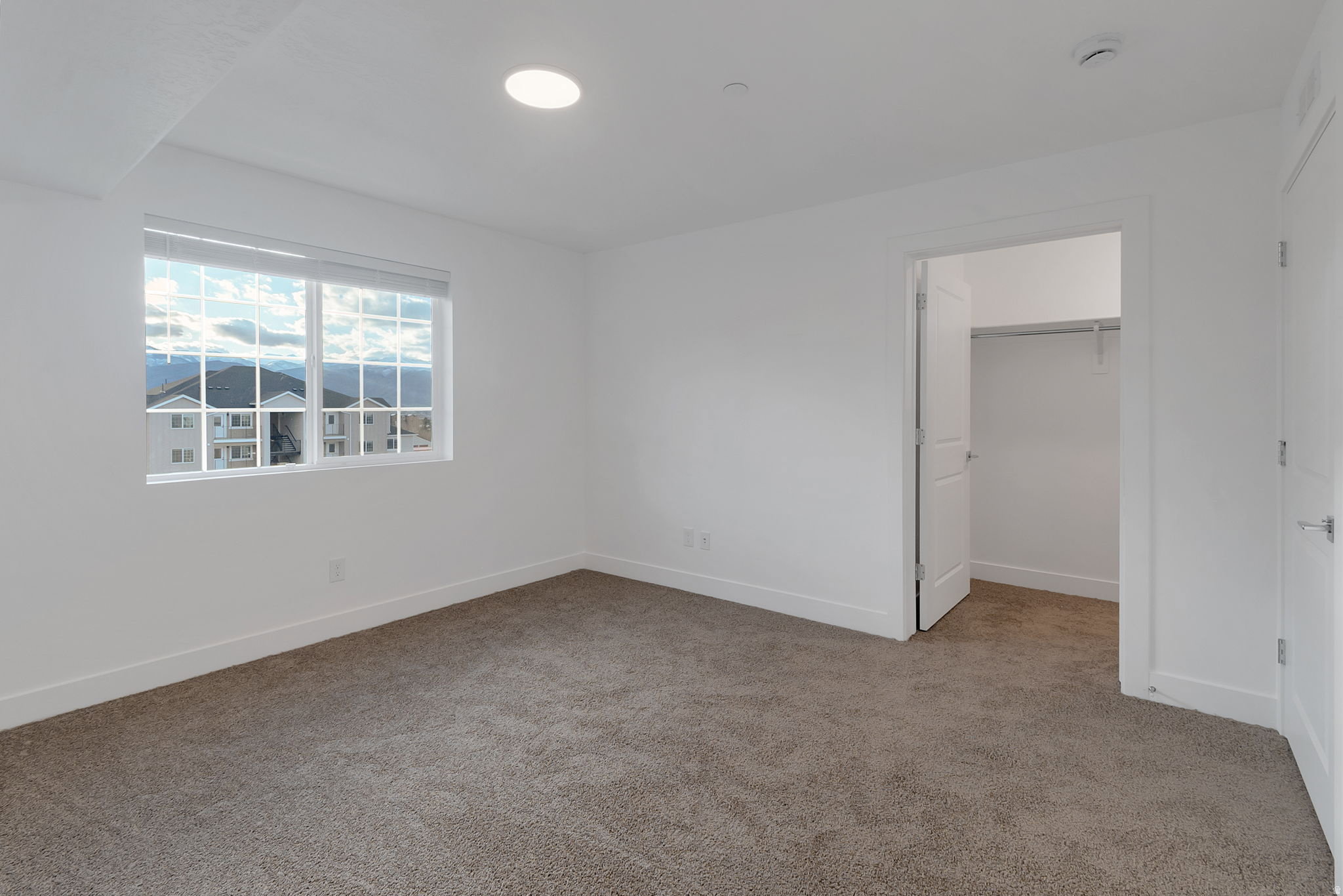 Room featuring neutral tone carpet flooring, white painted walls, a window with grid pattern, and a recessed ceiling light