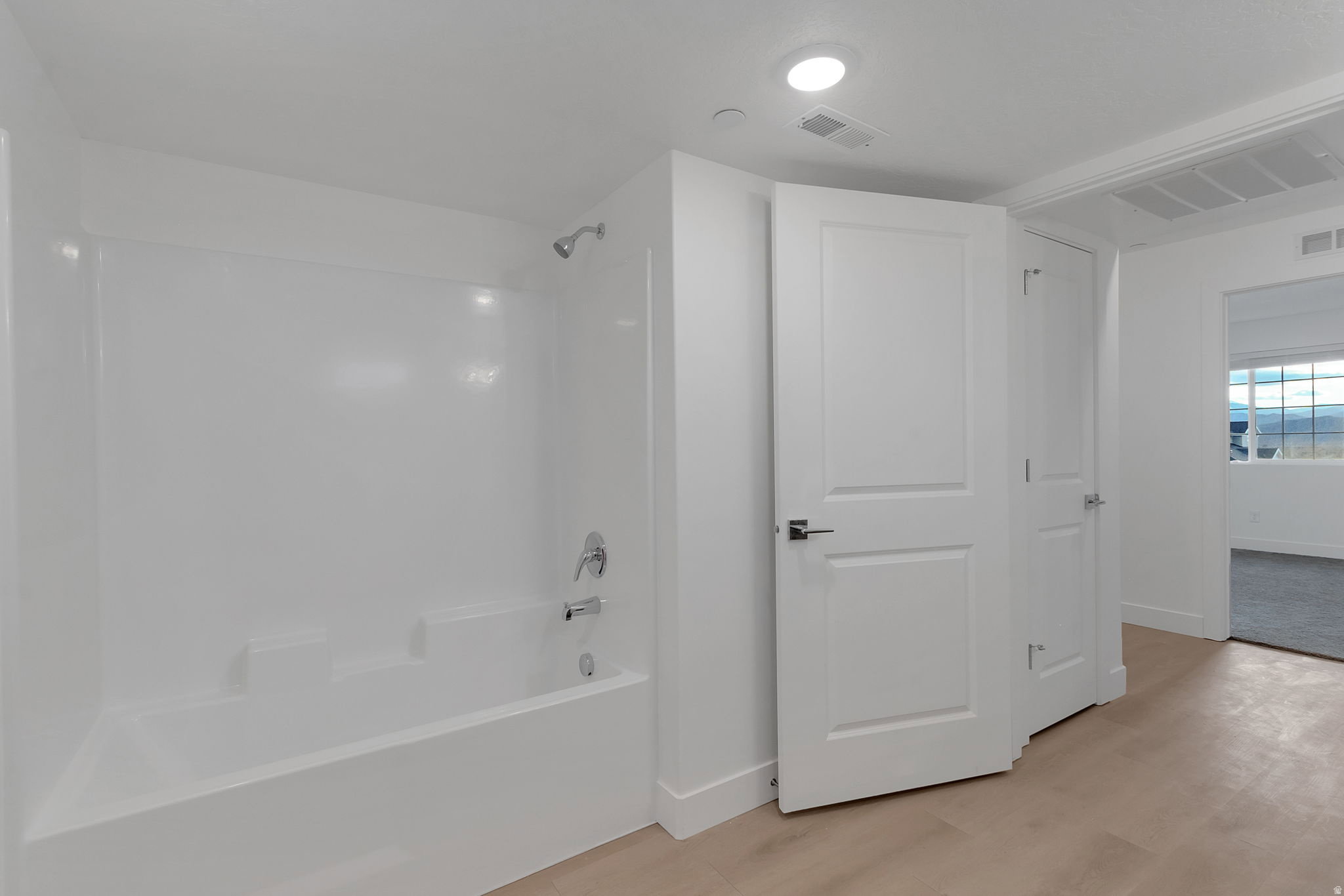 White tub and shower combination with chrome fixtures