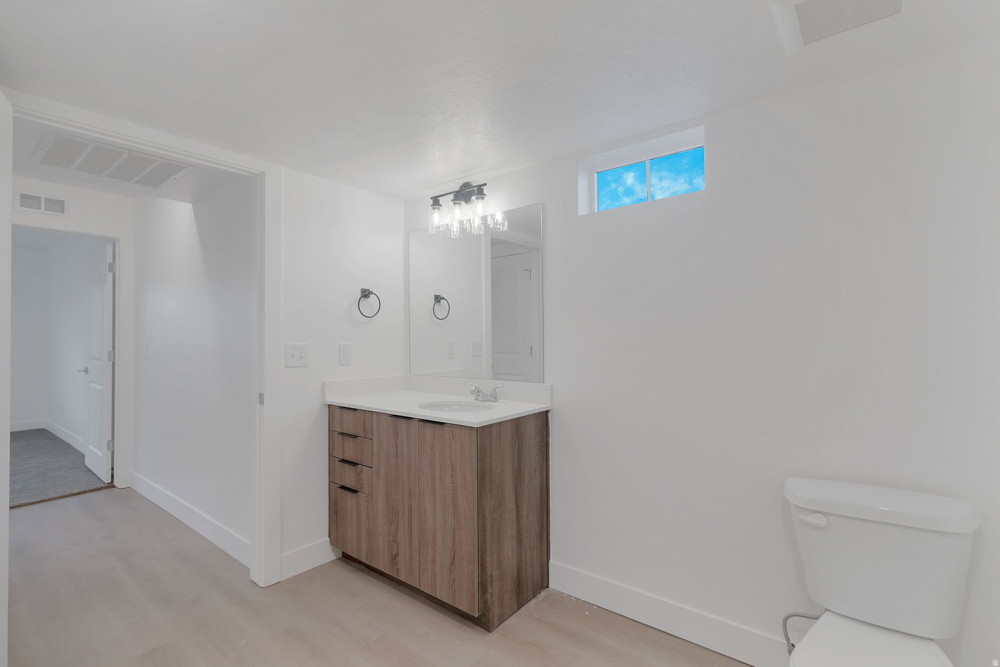Bathroom featuring a single vanity with wood-finish cabinetry, a white countertop, and an undermount sink