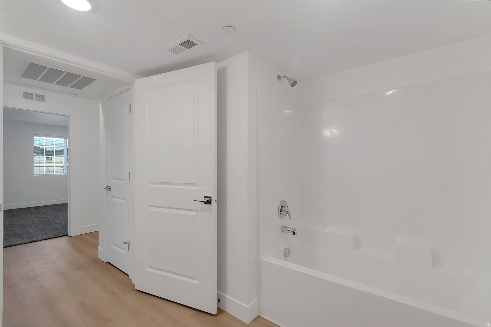 White fiberglass tub and shower combination with chrome fixtures