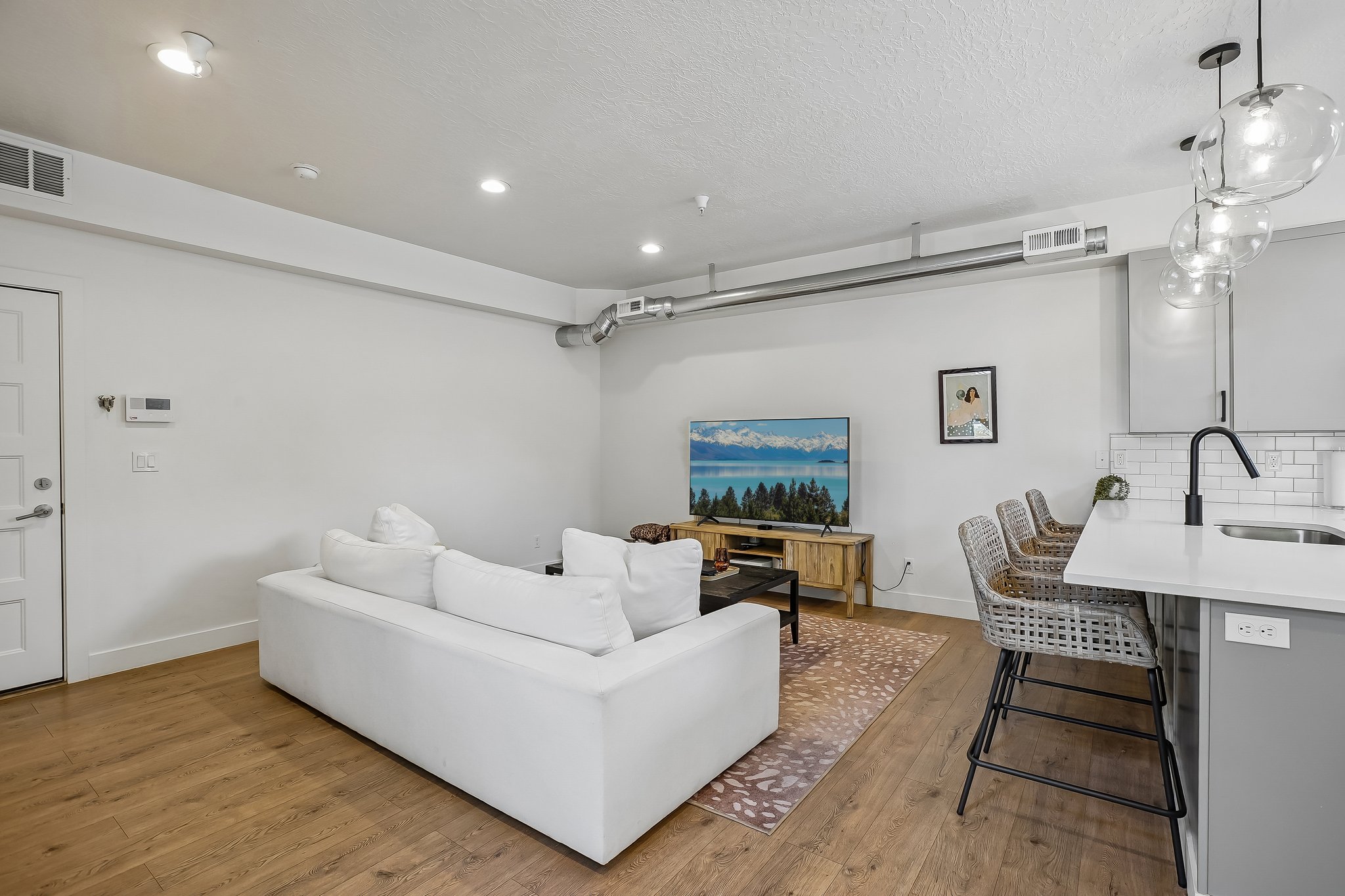 Open-concept living area featuring wood-finish flooring, recessed lighting, and exposed ductwork