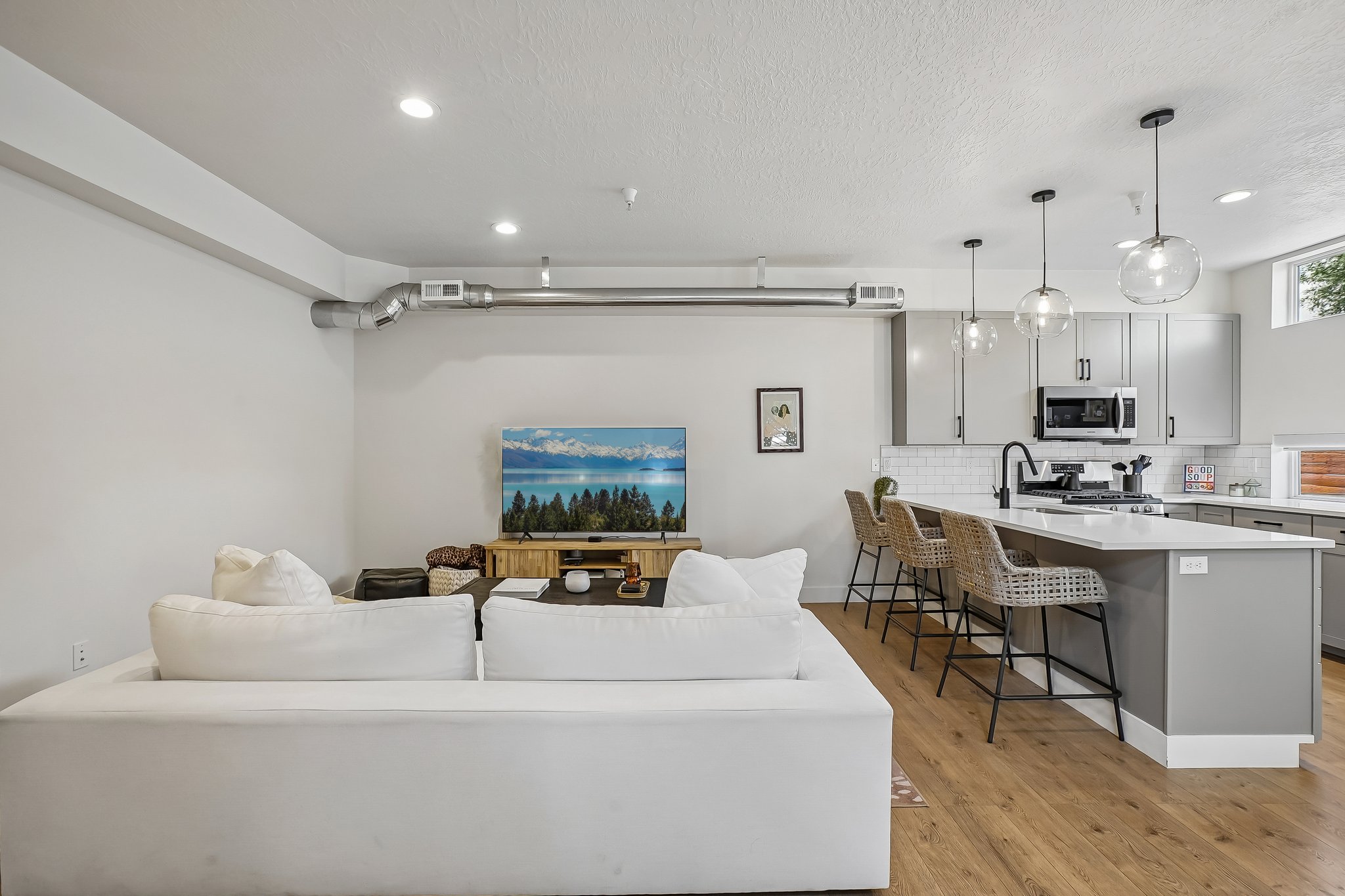 Open-concept living space featuring wood-finish flooring, recessed lighting, and exposed ductwork