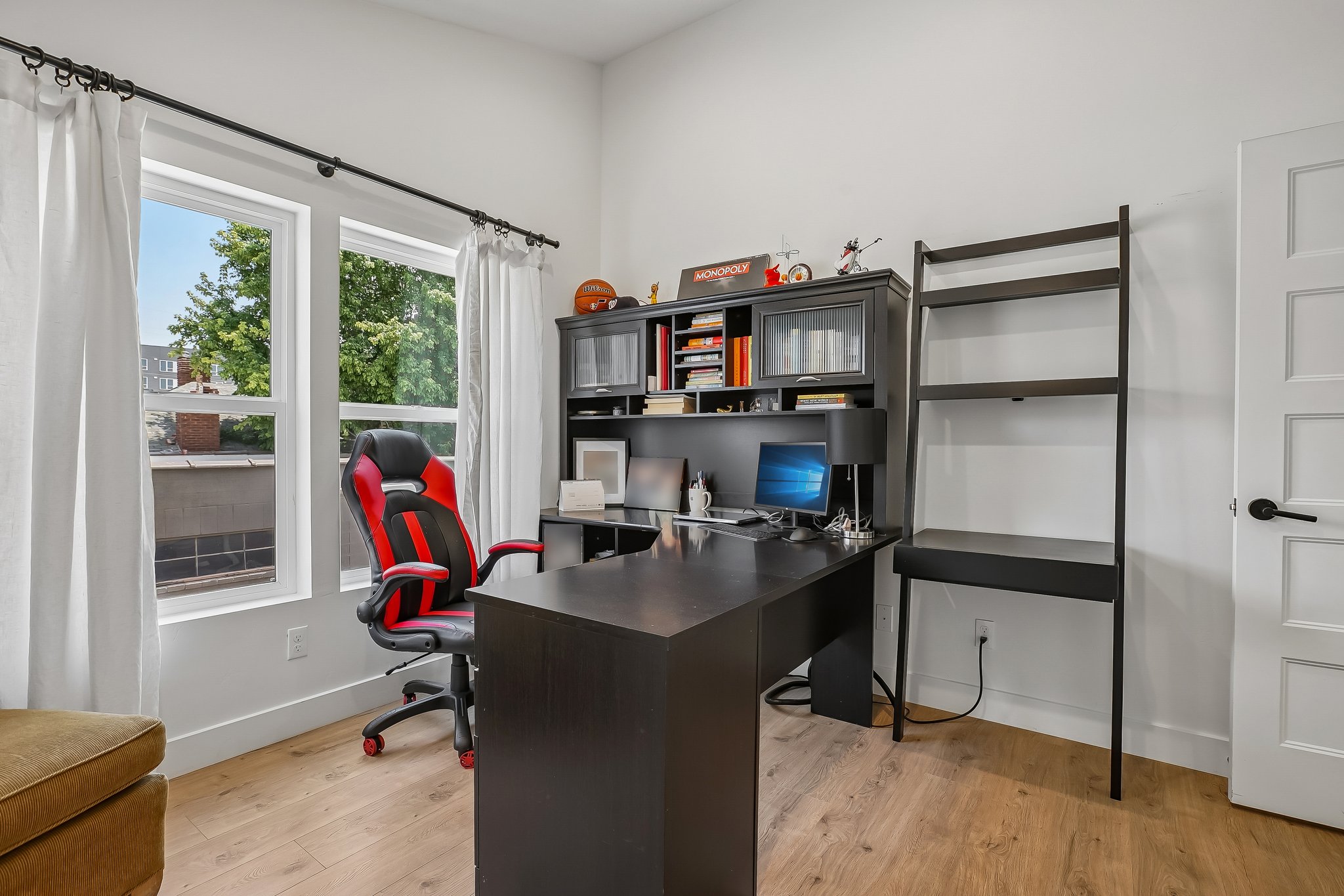 Bright room featuring wood-finish flooring, white walls, and two large windows with white trim