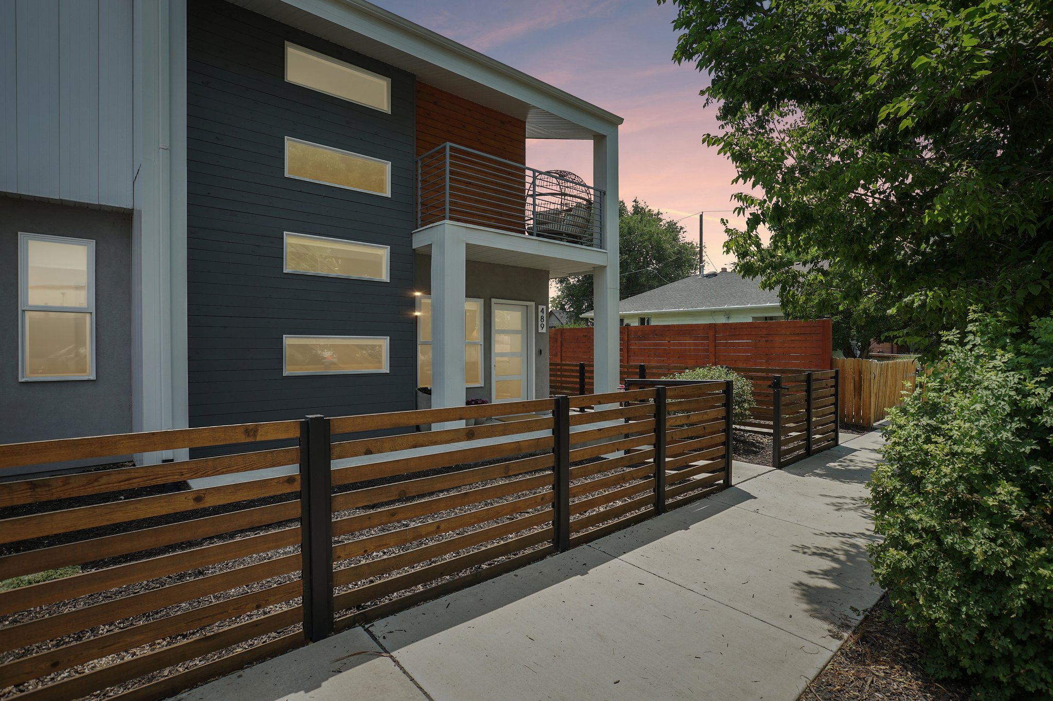 Contemporary exterior featuring dark siding with horizontal accents, multiple rectangular windows, and a second-story balcony