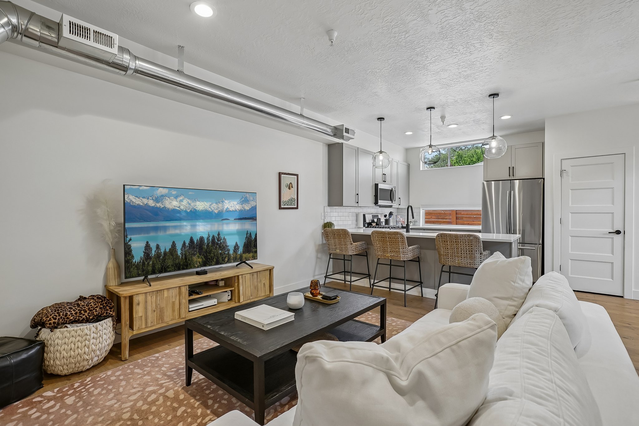 Open-concept living space featuring wood-finish flooring, recessed lighting, and exposed ductwork