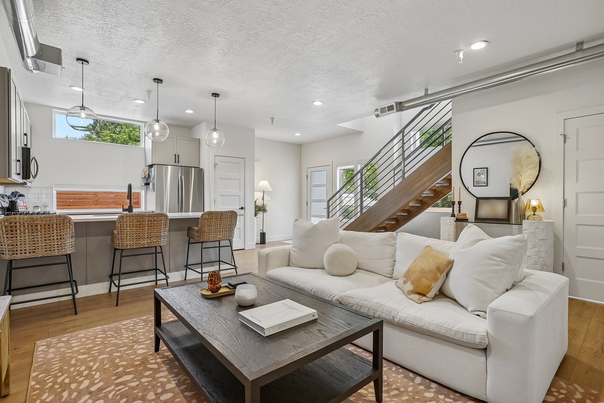 Open-concept living space featuring a modern kitchen with a large island, stainless steel appliances, and pendant lighting