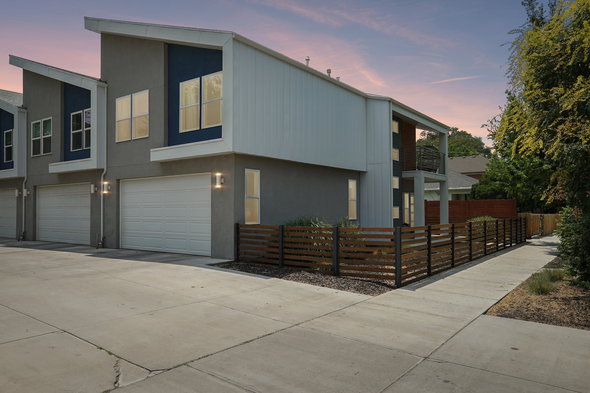 Contemporary exterior featuring a peaked roofline, gray stucco, and blue accents
