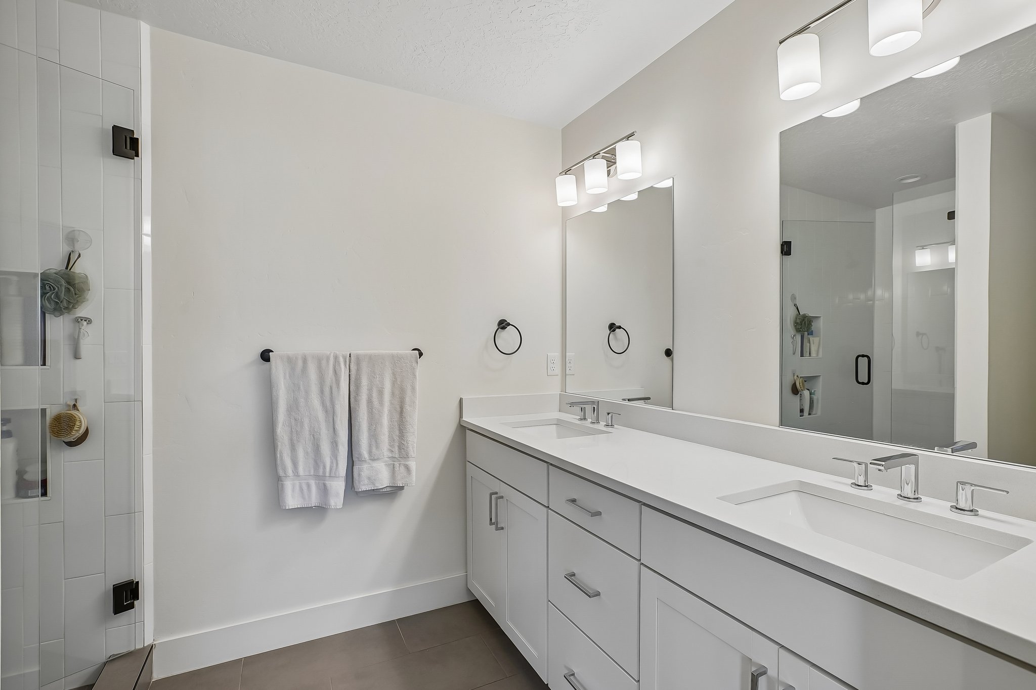 Dual vanity with white cabinetry, integrated sinks, and polished chrome fixtures