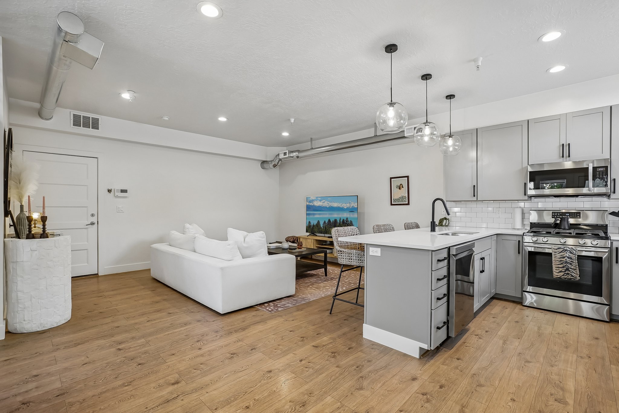 Open-concept living space featuring wood-finish flooring, recessed lighting, and exposed ductwork