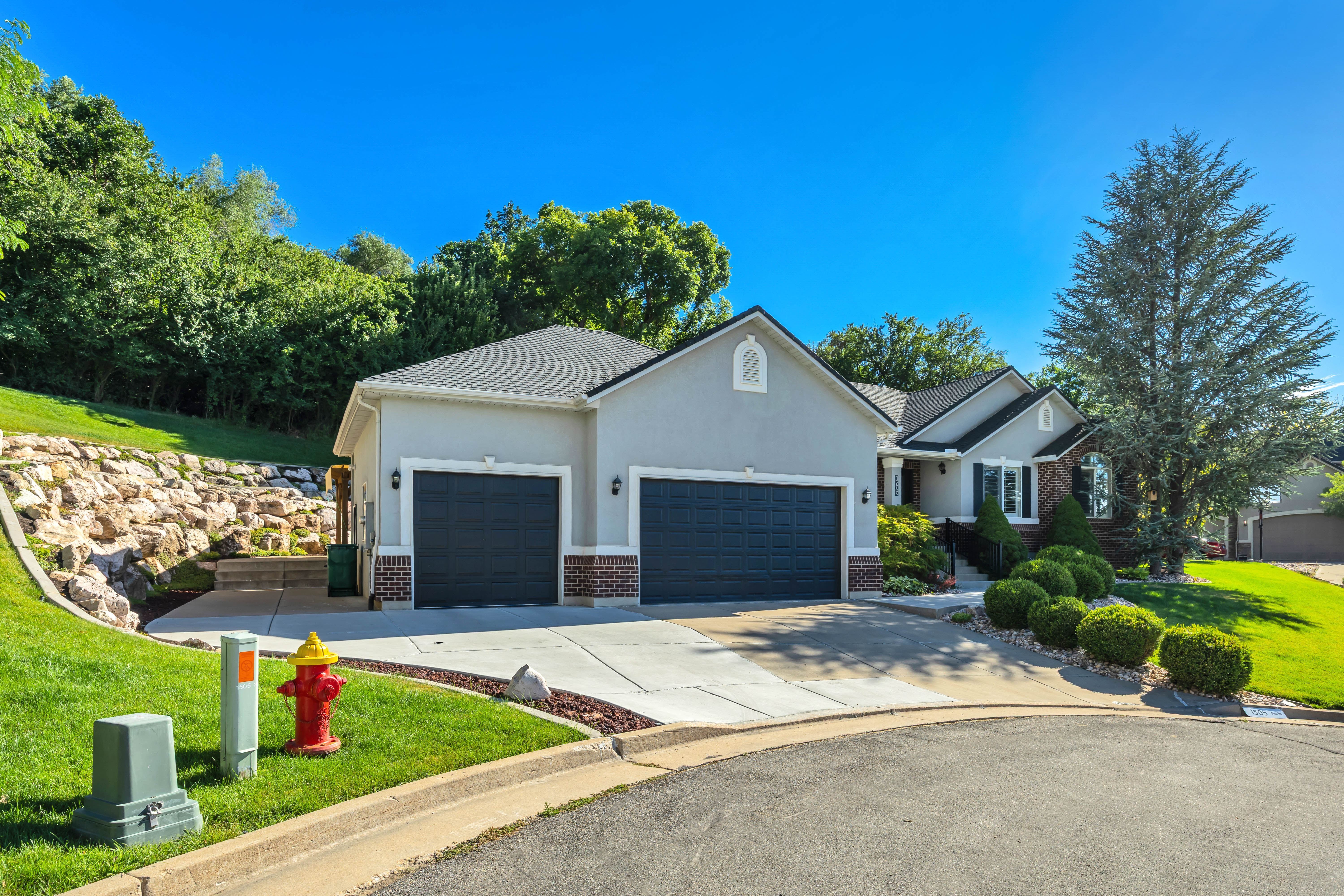 Stucco and brick residence featuring a three-car garage with dark paneled doors