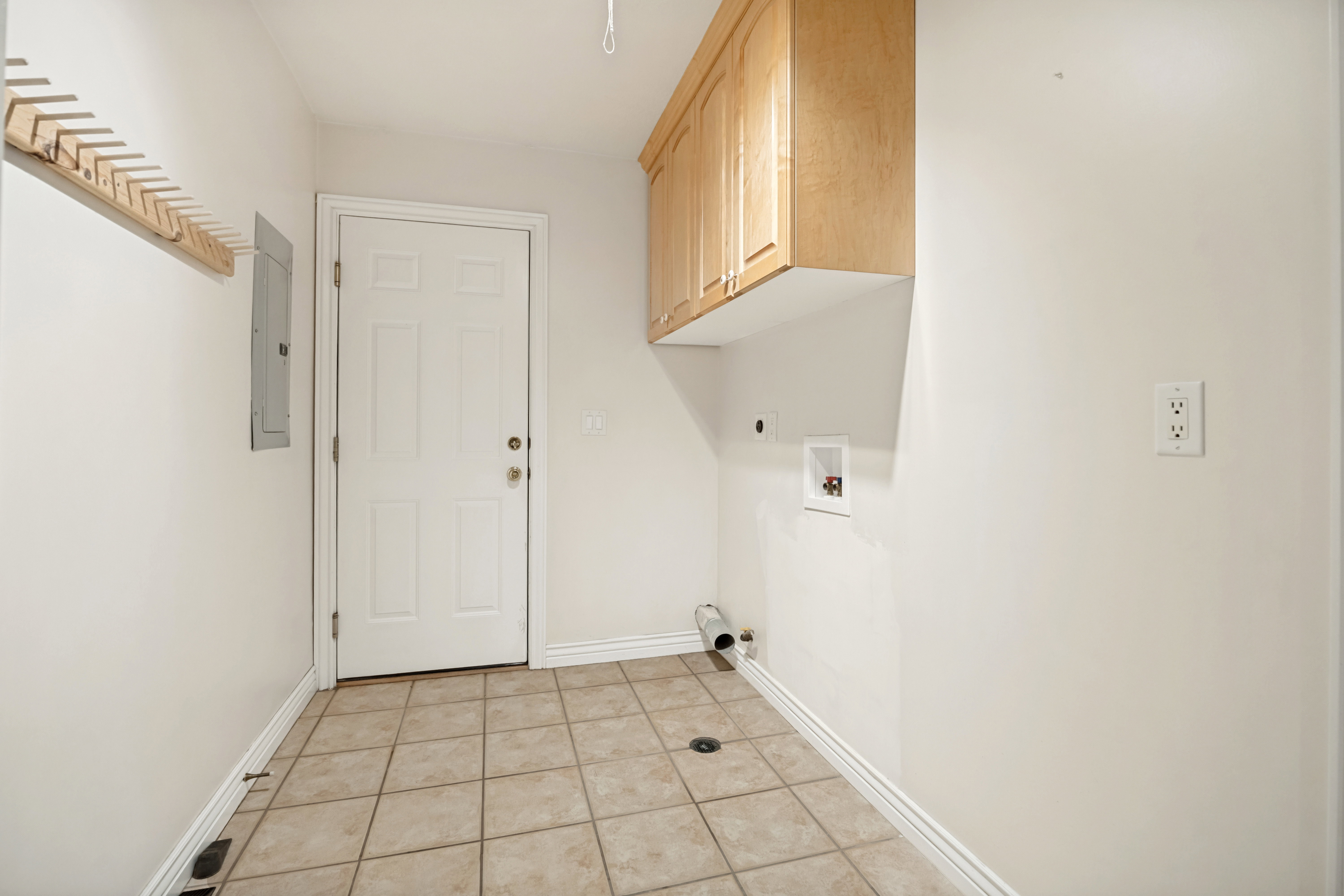 Laundry room featuring tile flooring, a paneled door, wall-mounted cabinetry, and appliance hookups