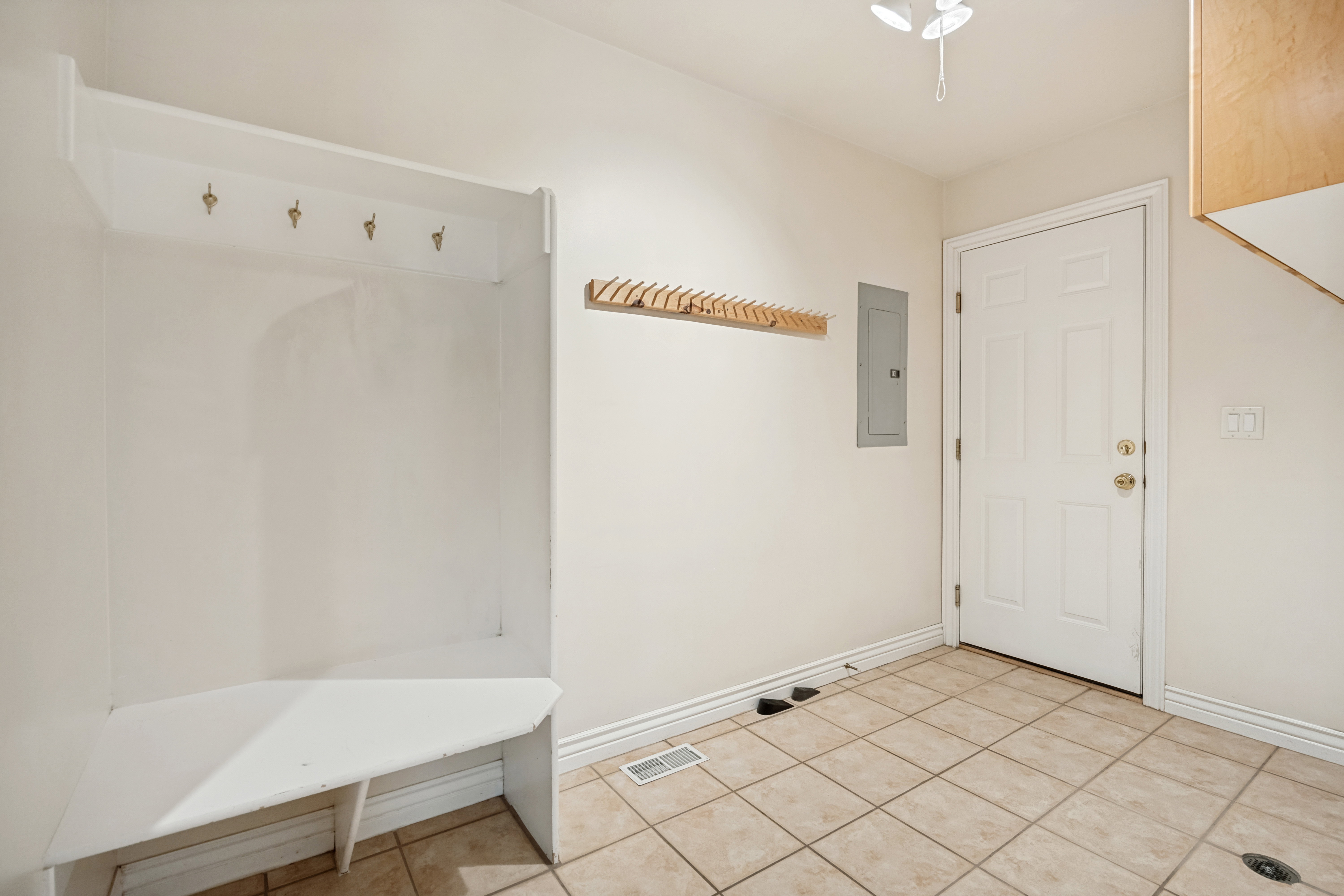 Laundry room with built-in bench with coat hooks, complemented by additional wall-mounted coat racks