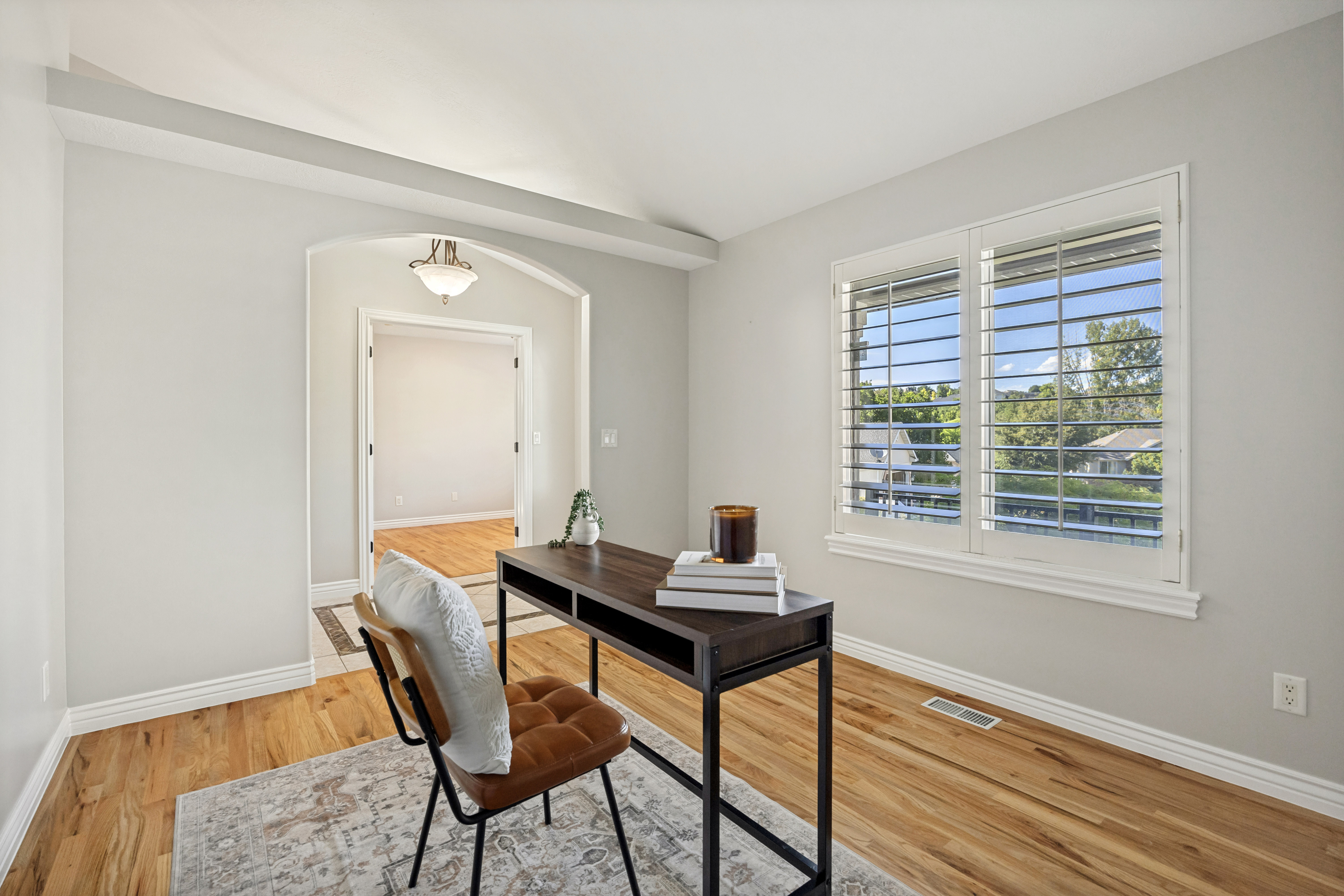 Large Entry Room that can also serve as a sitting room, office, or library with two large windows with plantation shutters, and an arched doorway