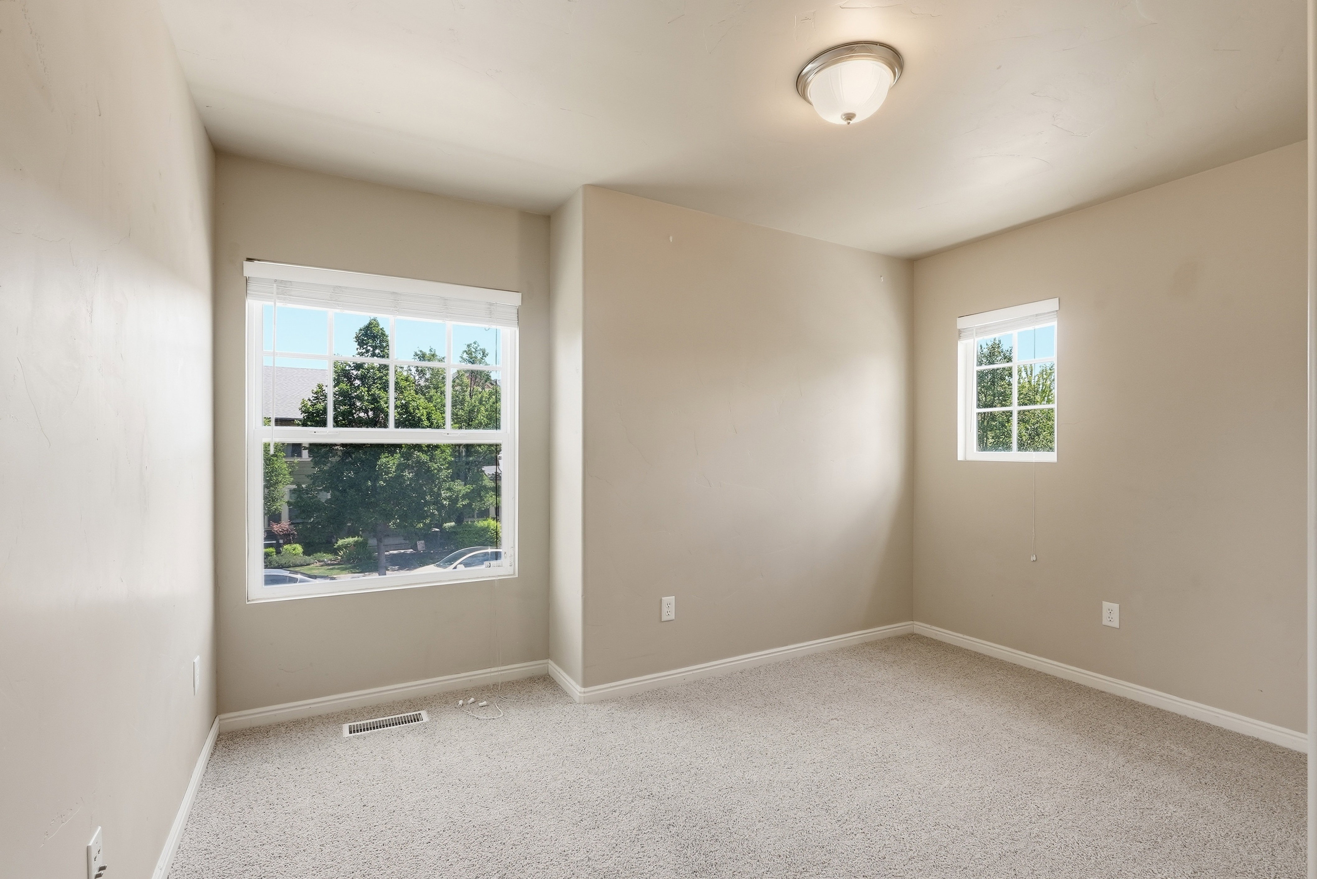 Carpeted room with neutral wall tones and multiple windows