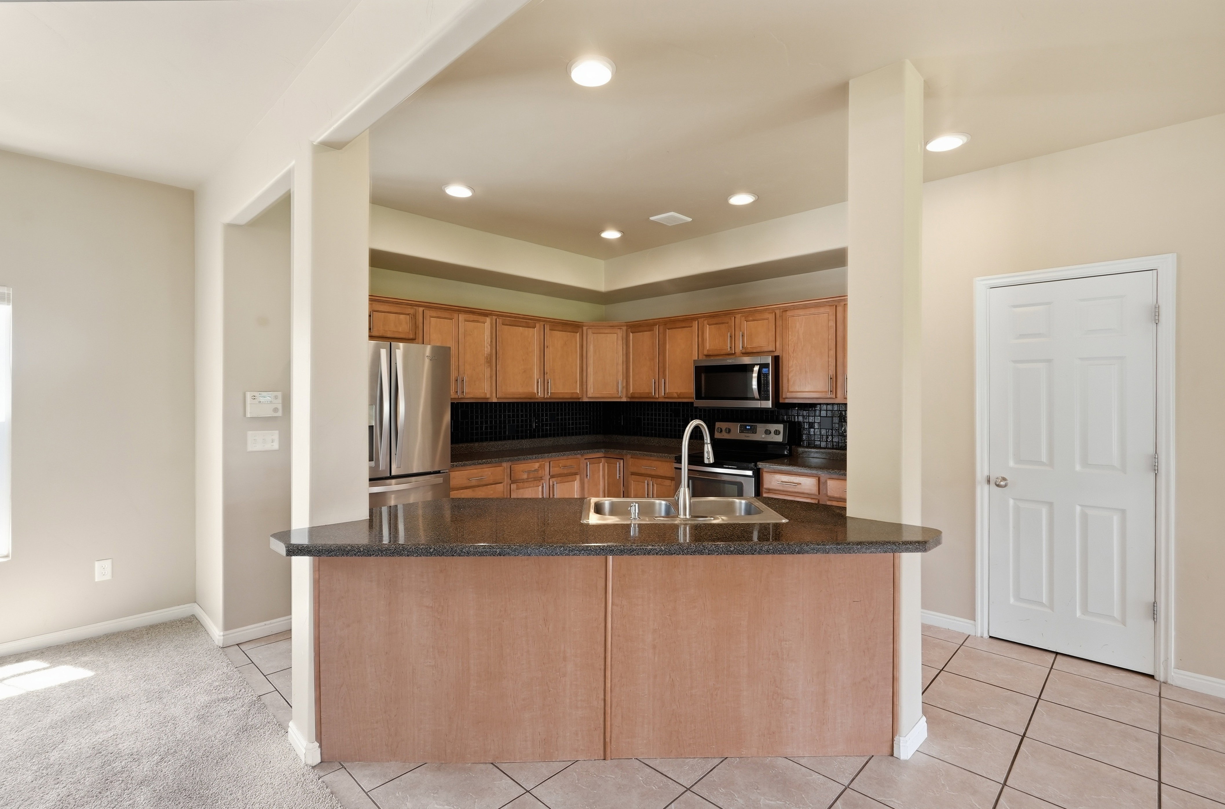 Kitchen featuring wood cabinetry, stainless steel appliances, dark stone-finish countertops, tile backsplash, and recessed lighting