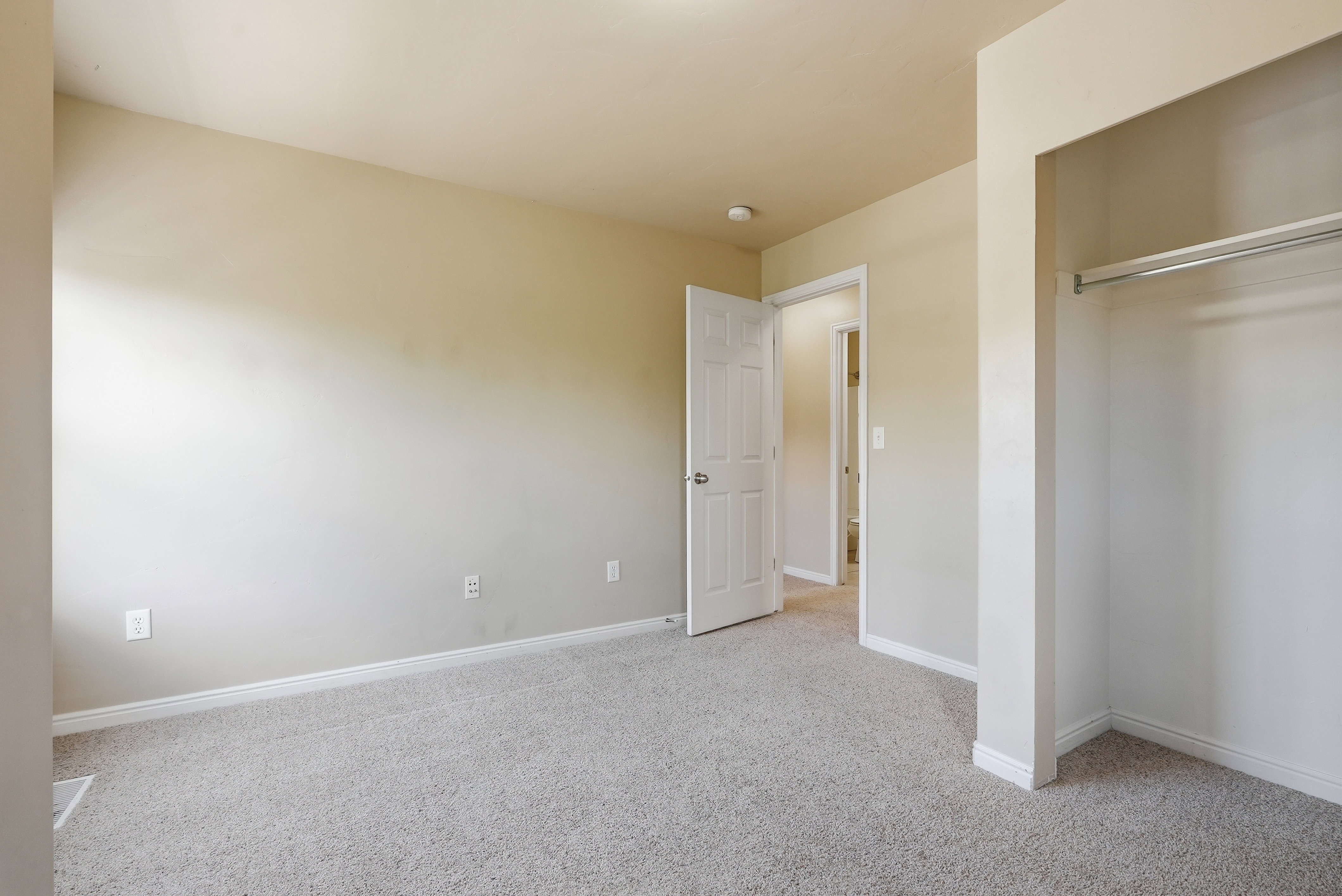 Neutral-toned room featuring light beige walls and gray carpet flooring