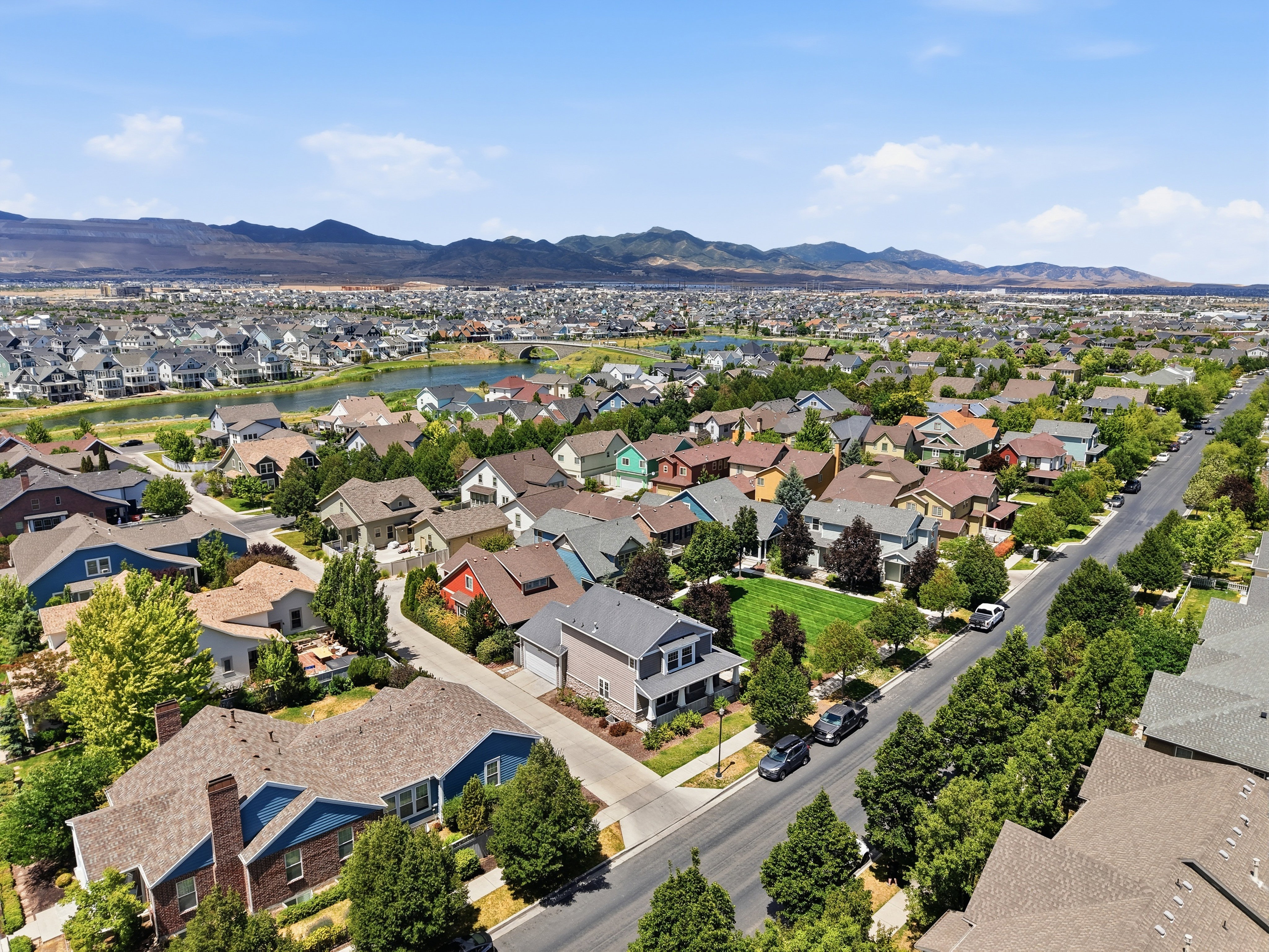 Expansive residential community with diverse architecture, abundant mature trees, and a prominent water feature