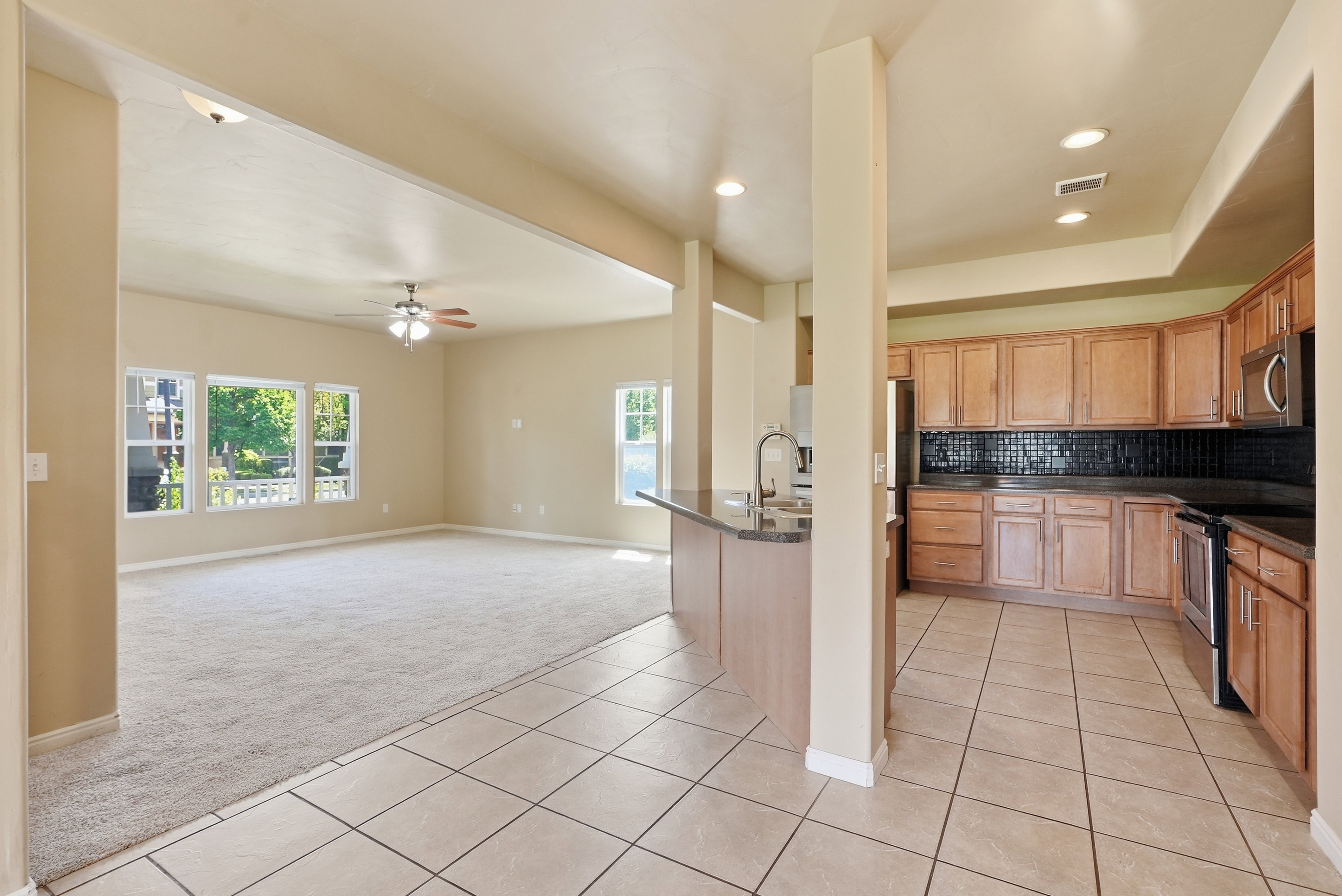 Kitchen and living area featuring a breakfast bar, recessed lighting, tile flooring, and carpeted living space with multiple windows