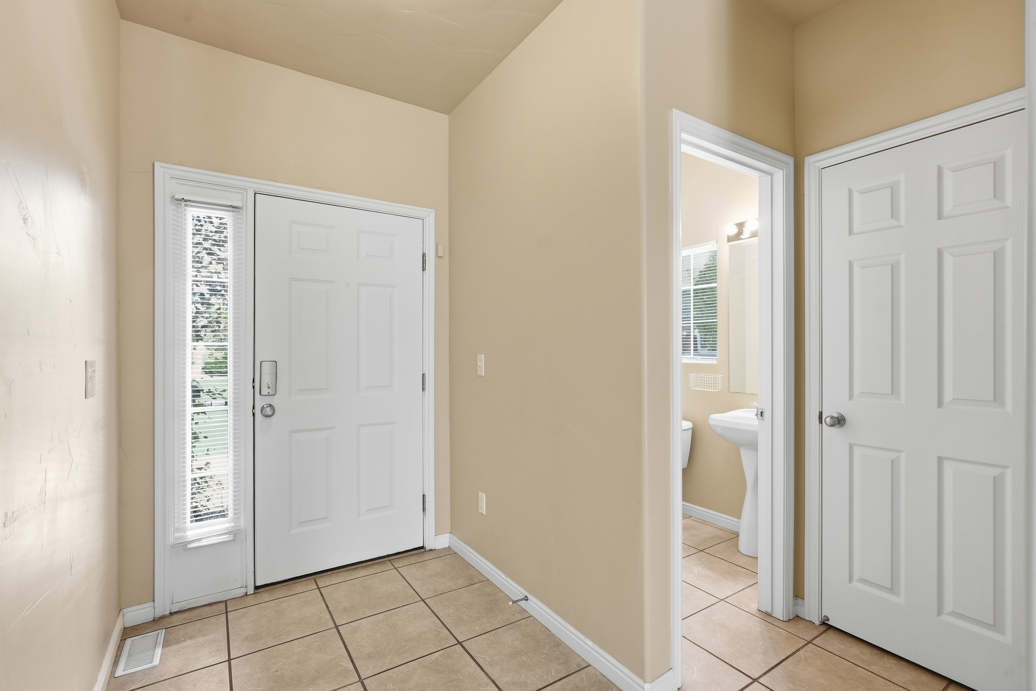 Entryway featuring light-toned tile flooring, a white paneled front door, and a sidelight window