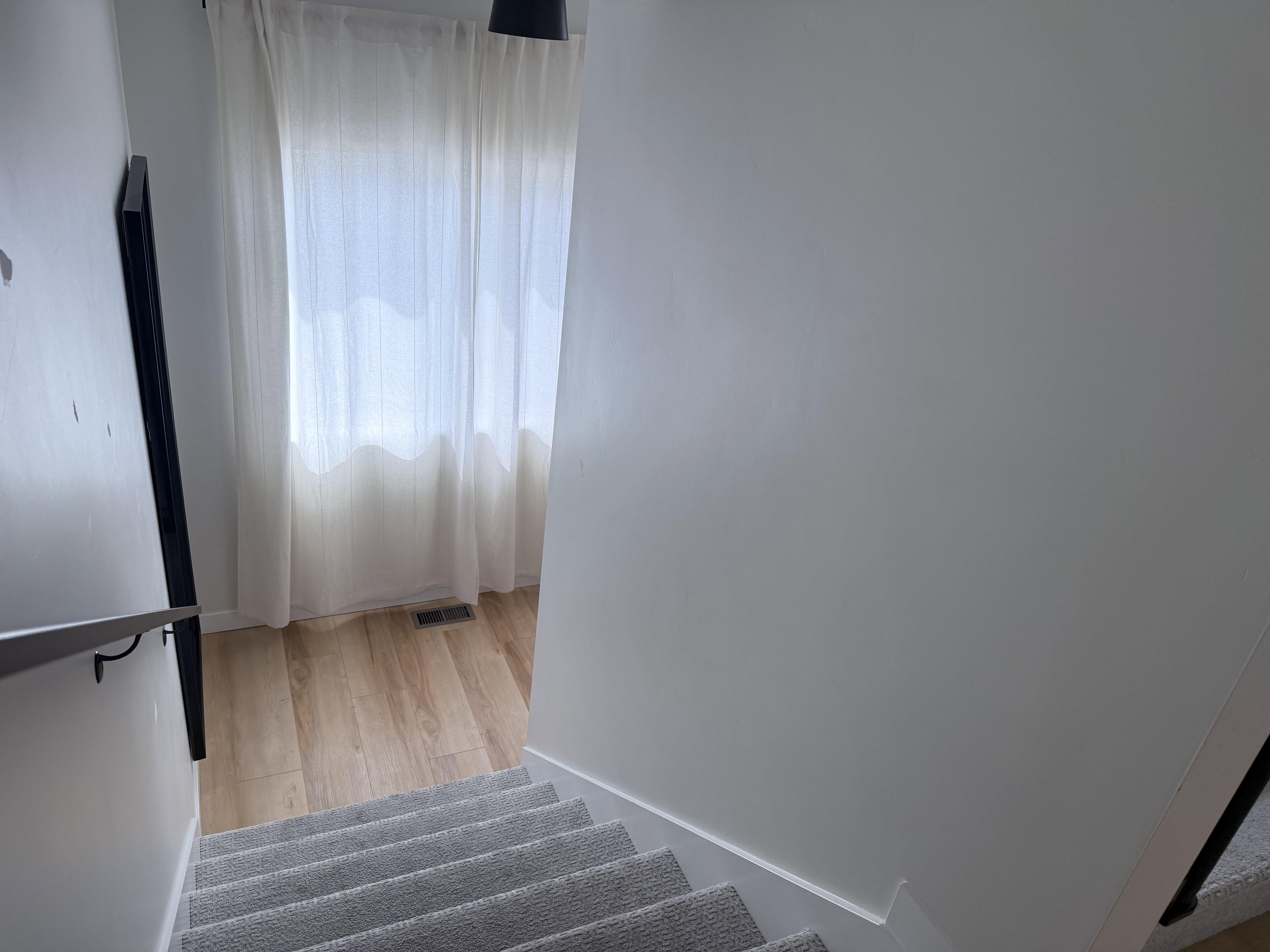 Carpeted staircase with a contemporary metal handrail and light-toned wood-finish flooring