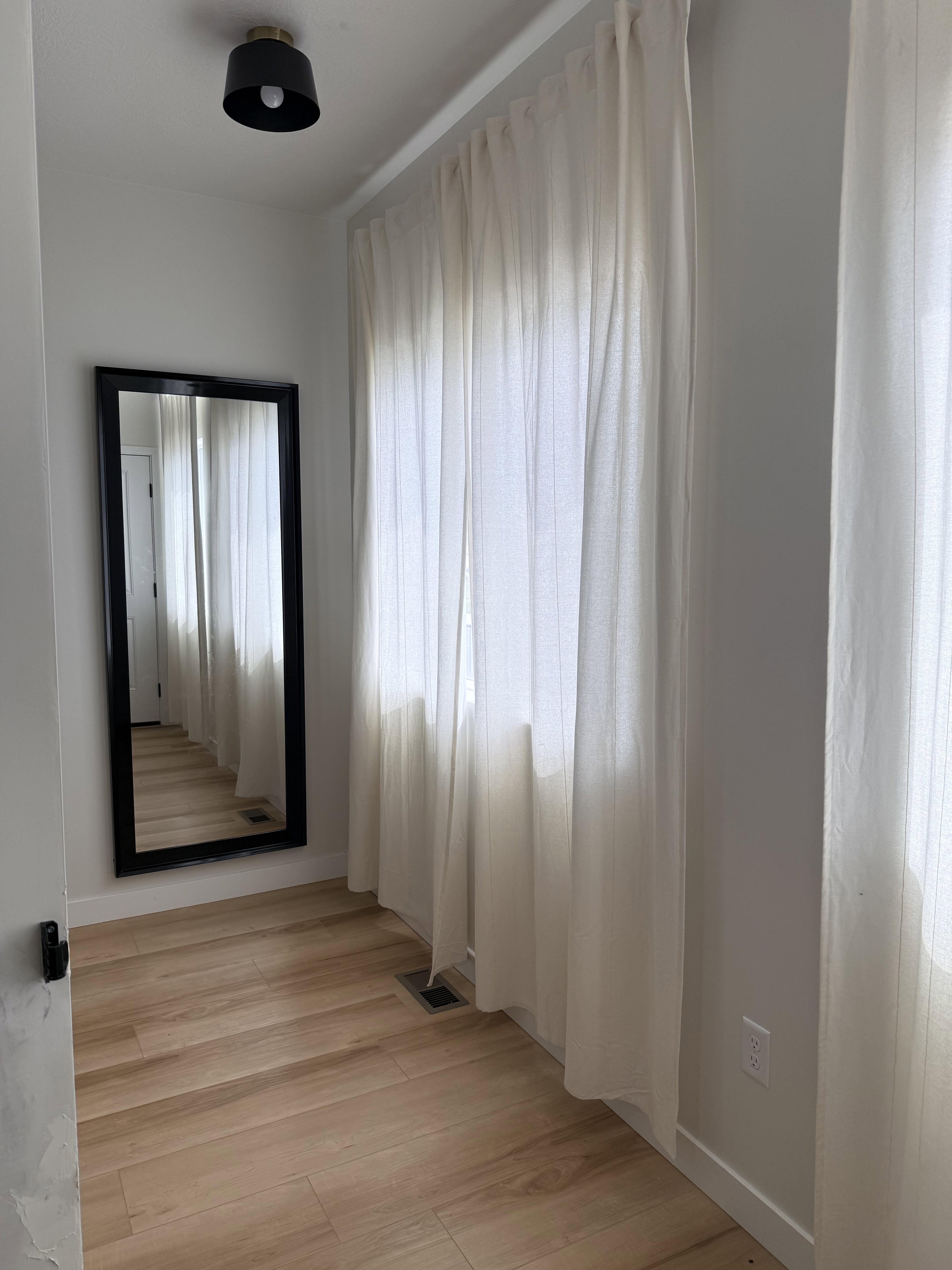 Hallway featuring wood-finish flooring and a full-length mirror